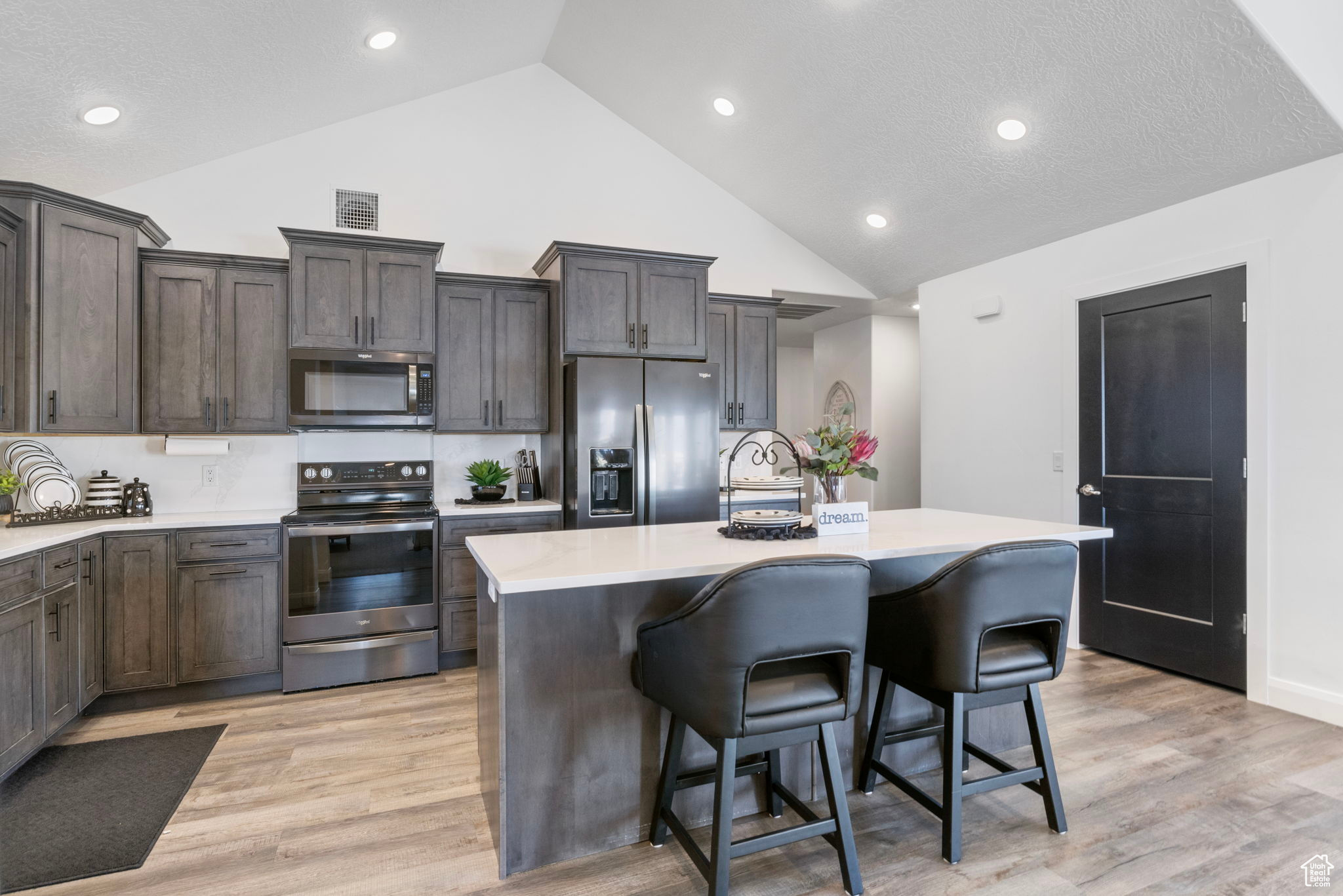 Kitchen featuring a kitchen breakfast bar, a kitchen island with sink, appliances with stainless steel finishes, and light hardwood / wood-style flooring