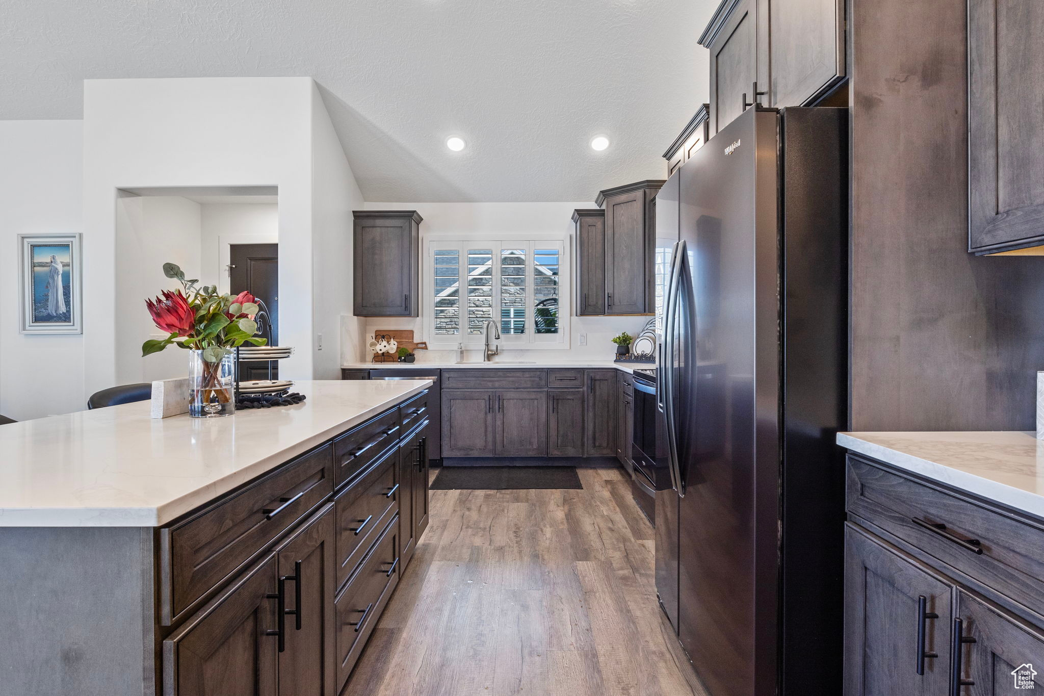 Kitchen featuring sink, a center island, dark wood-type flooring, stainless steel refrigerator with ice dispenser, and dark brown cabinets