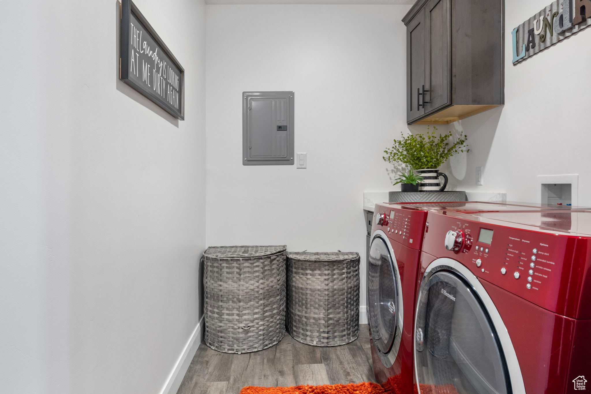 Laundry room with cabinets, hardwood / wood-style flooring, washing machine and dryer, and electric panel