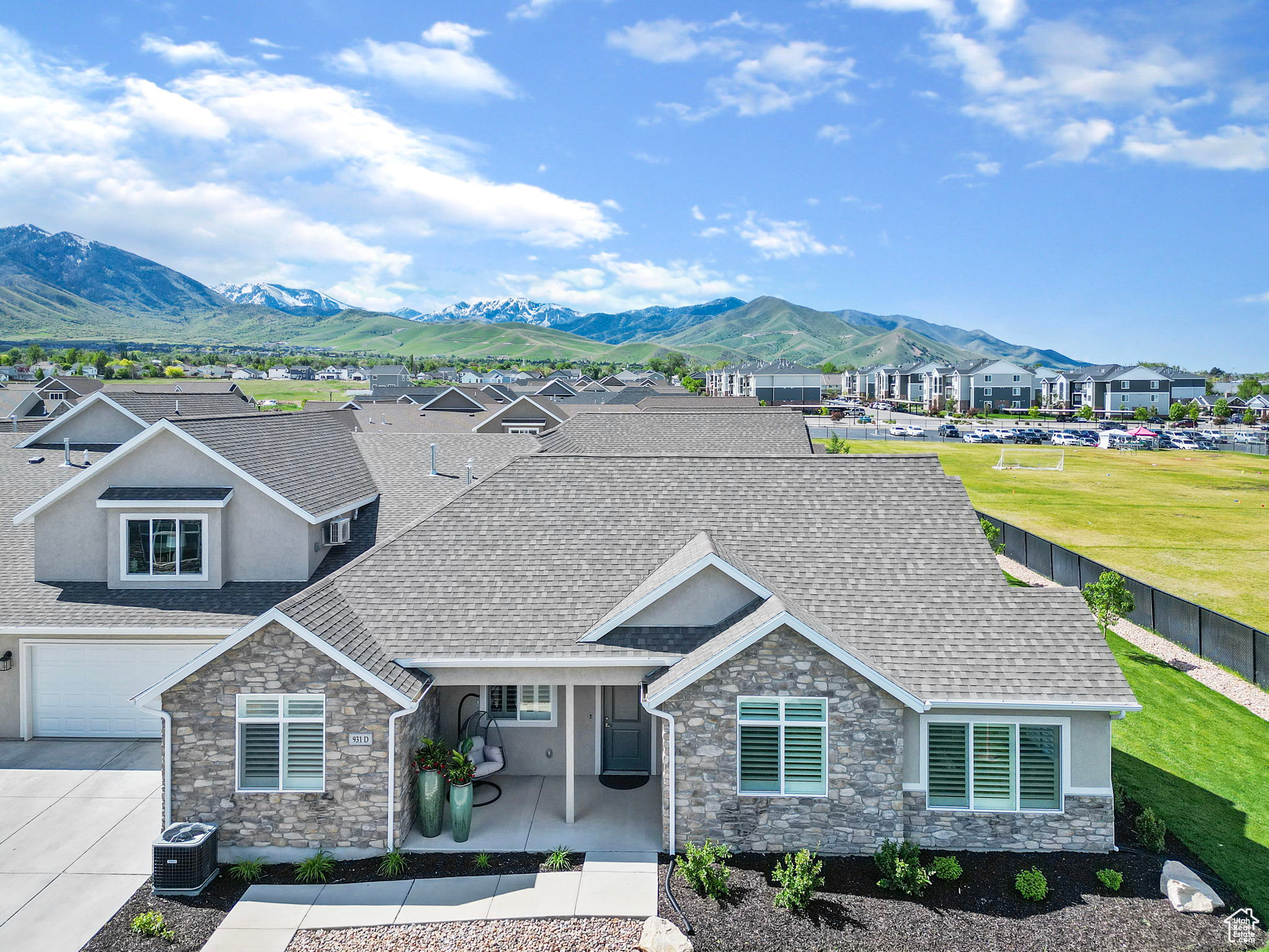 View of front facade featuring a mountain view, central air condition unit, a patio area, a front lawn, and a garage