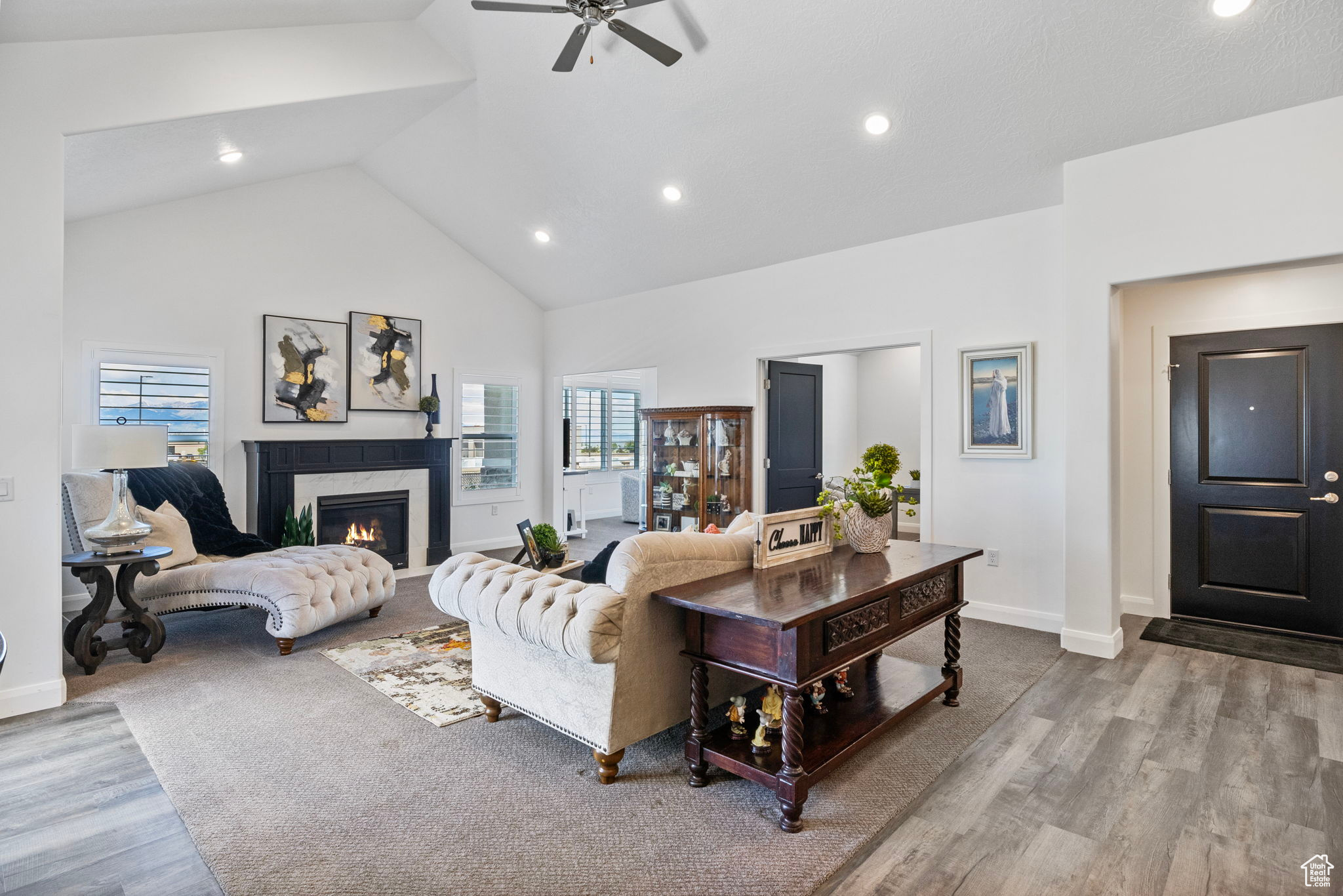 Living room with ceiling fan, light hardwood / wood-style flooring, a high end fireplace, and high vaulted ceiling