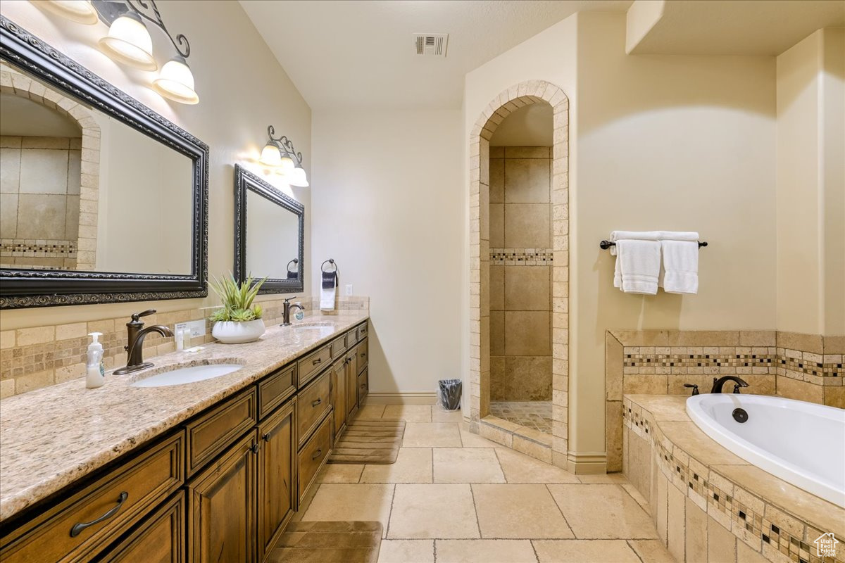Bathroom featuring tile patterned floors, vanity, and plus walk in shower