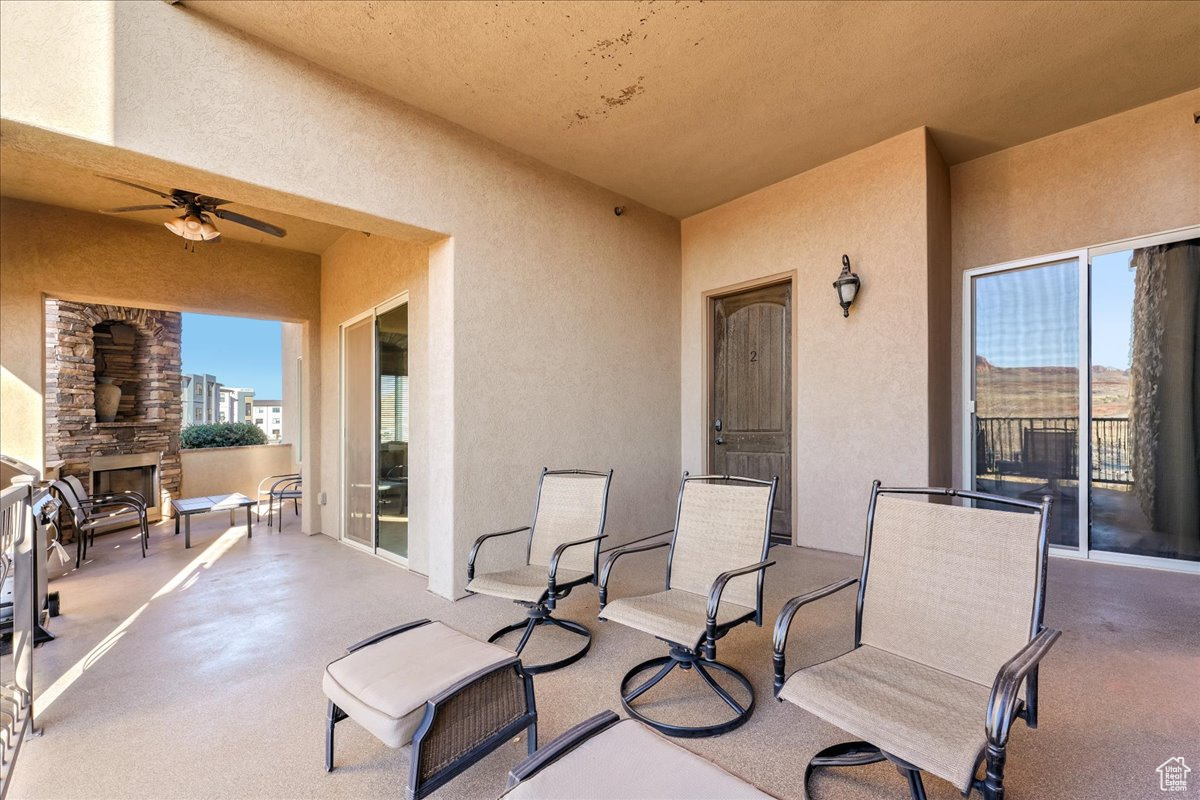 View of patio featuring an outdoor stone fireplace and ceiling fan
