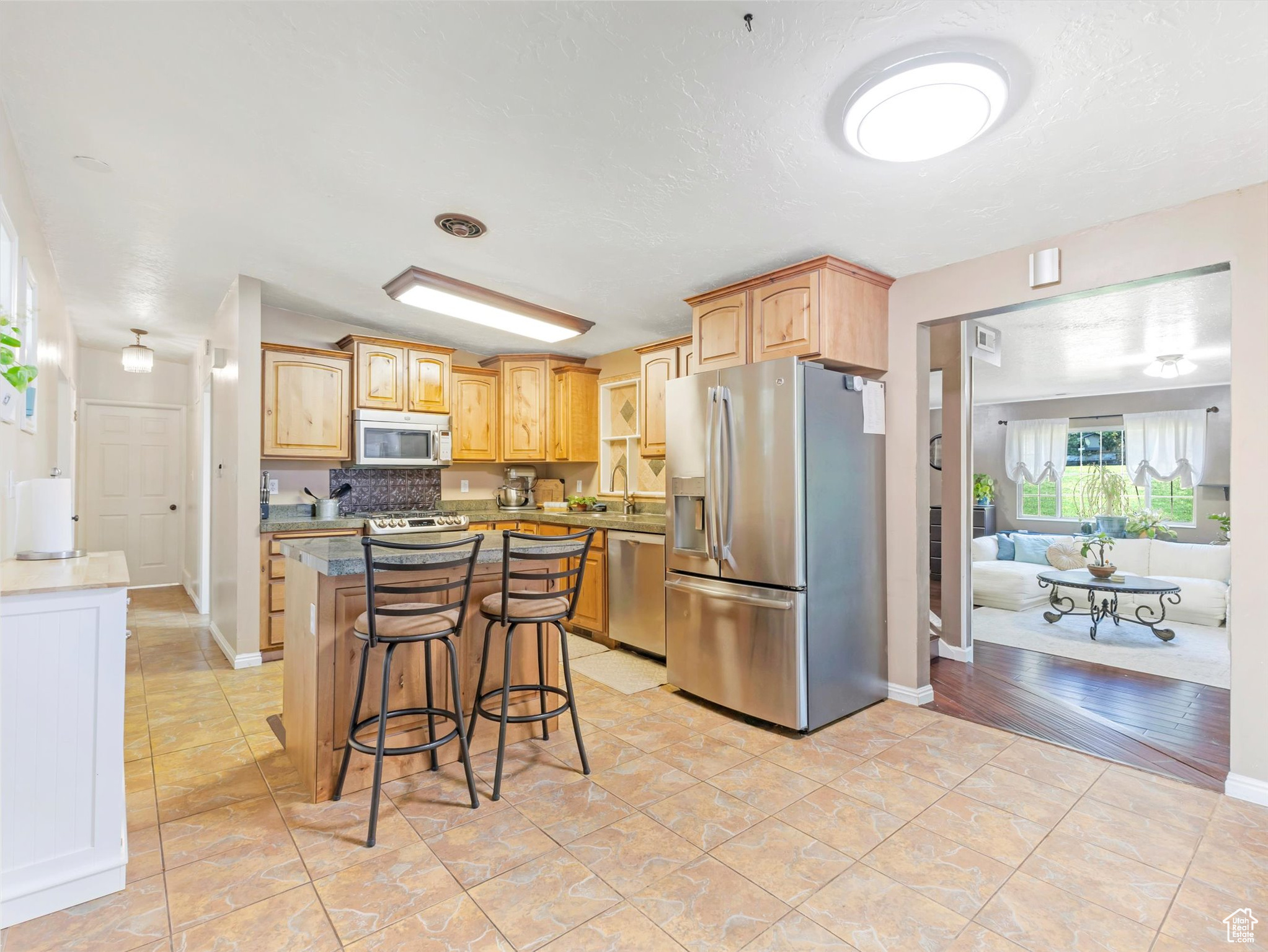 Kitchen featuring sink, stainless steel appliances, backsplash, a kitchen bar, and a kitchen island