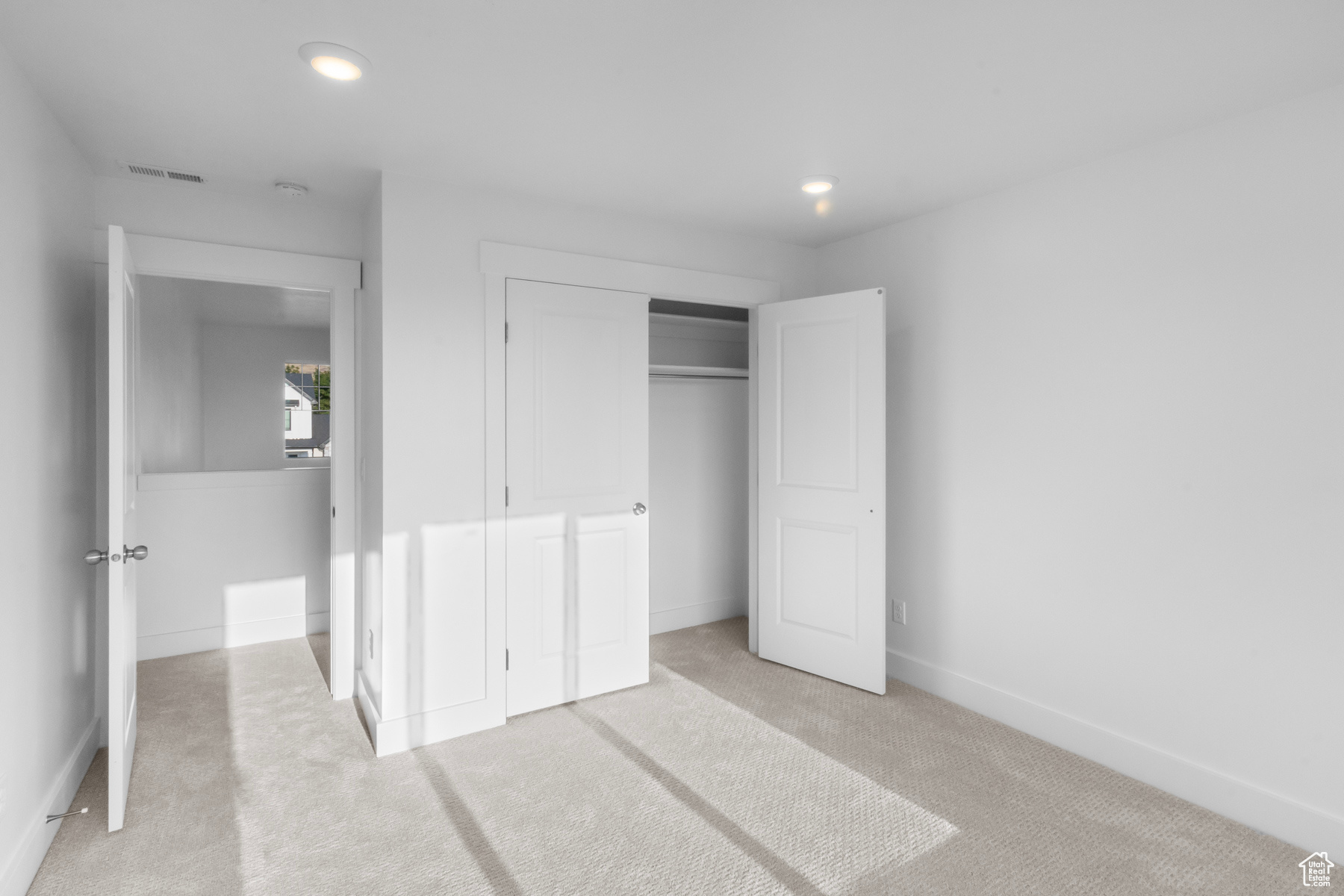 Unfurnished bedroom with light carpet and a closet