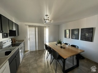Kitchen featuring an inviting chandelier, white range with electric cooktop, plenty of natural light, and dark tile patterned flooring