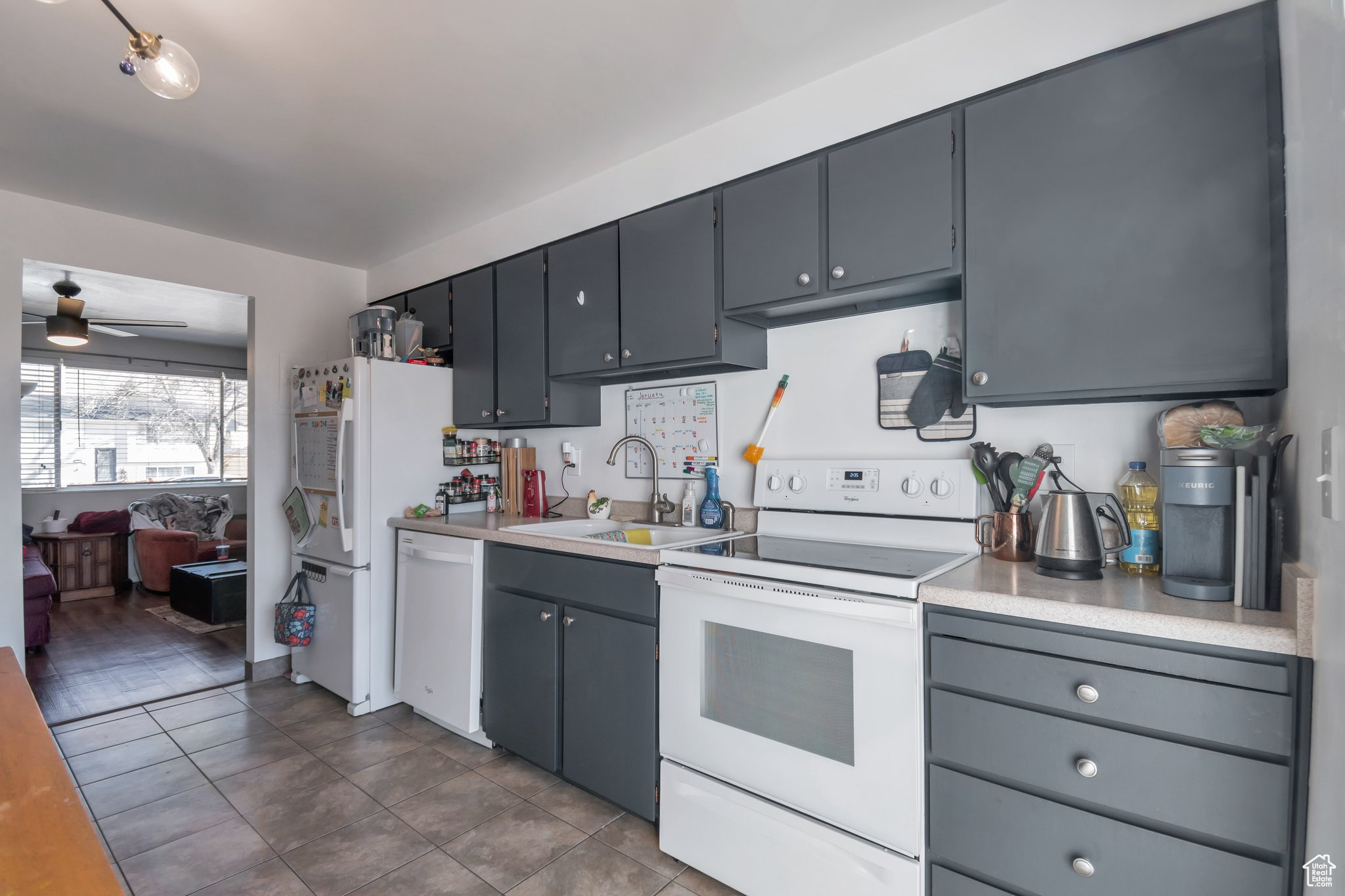 Kitchen with ceiling fan, light tile patterned floors, sink, and white appliances