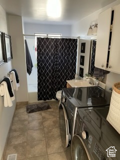 Bathroom featuring tile patterned flooring, sink, and independent washer and dryer