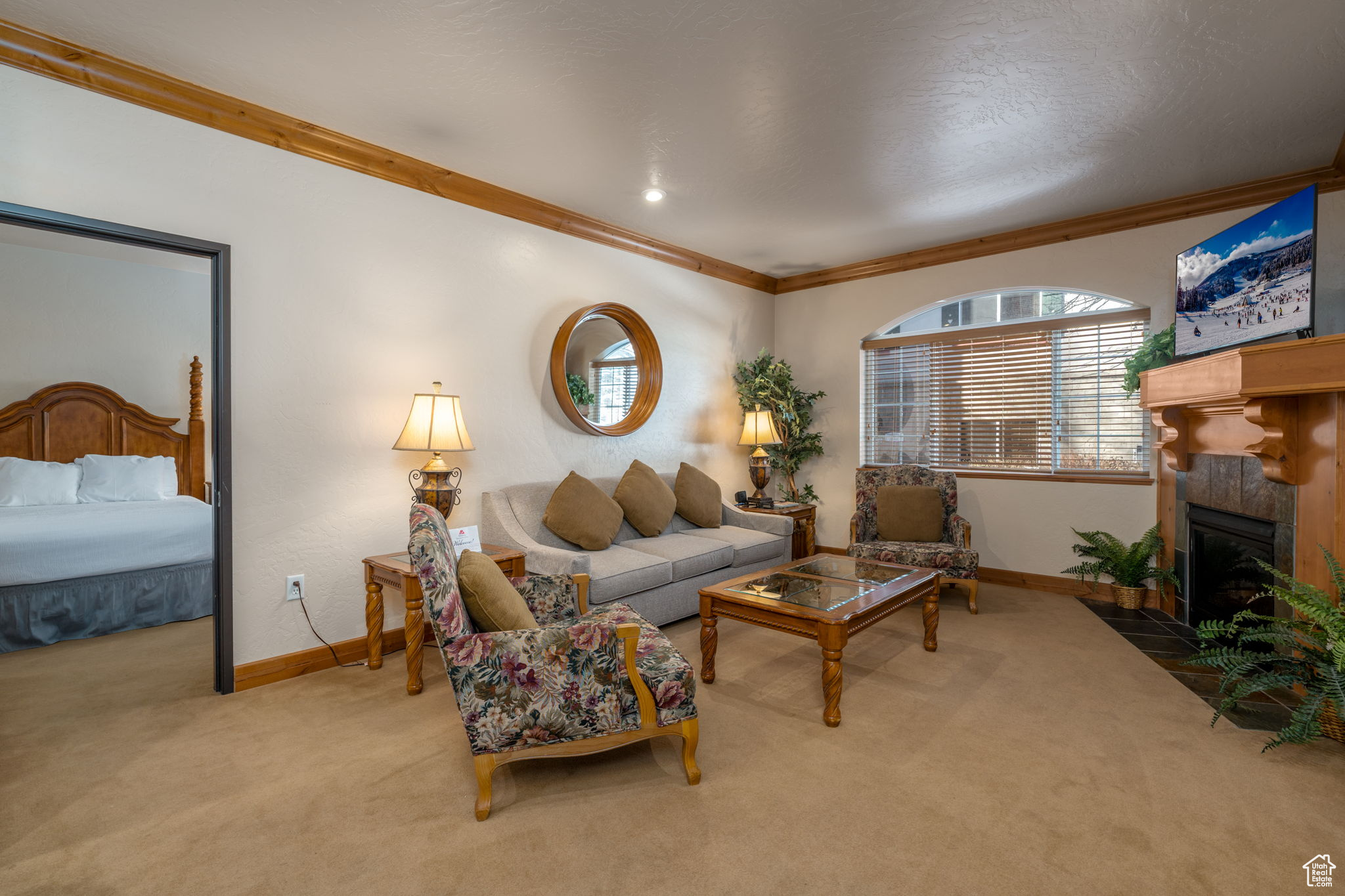 Carpeted living room featuring crown molding and a tiled fireplace