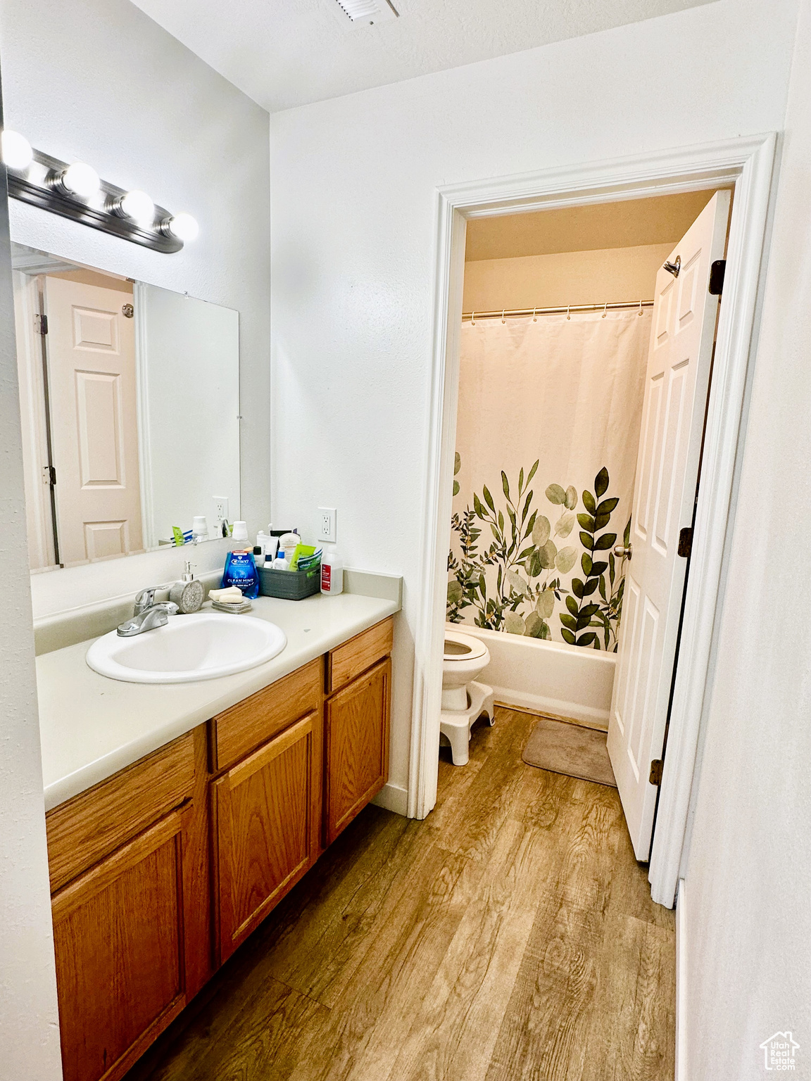 Primary Full bathroom featuring shower / bathtub combination with curtain, toilet, vanity, and hardwood / wood-style flooring