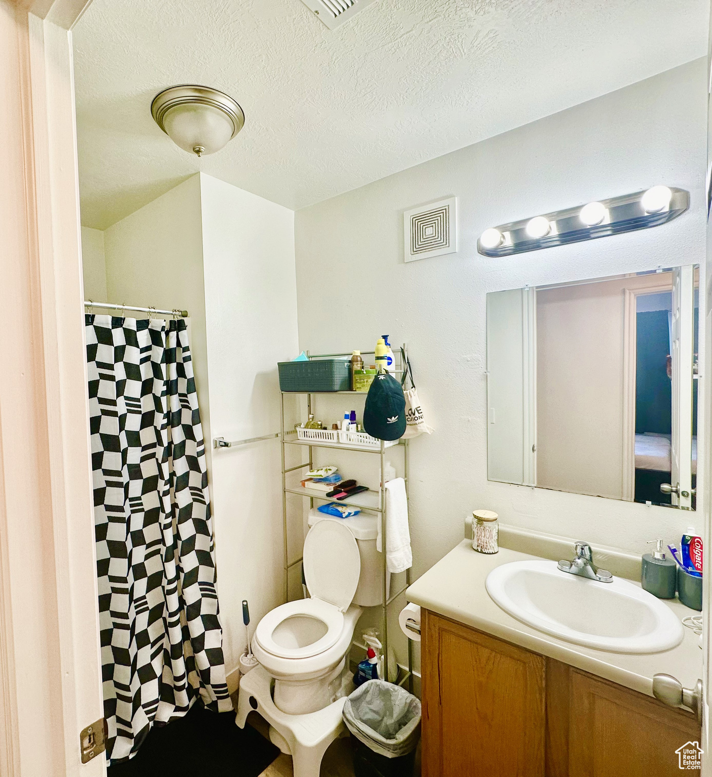 Bathroom with a textured ceiling, vanity, toilet, and a shower with curtain