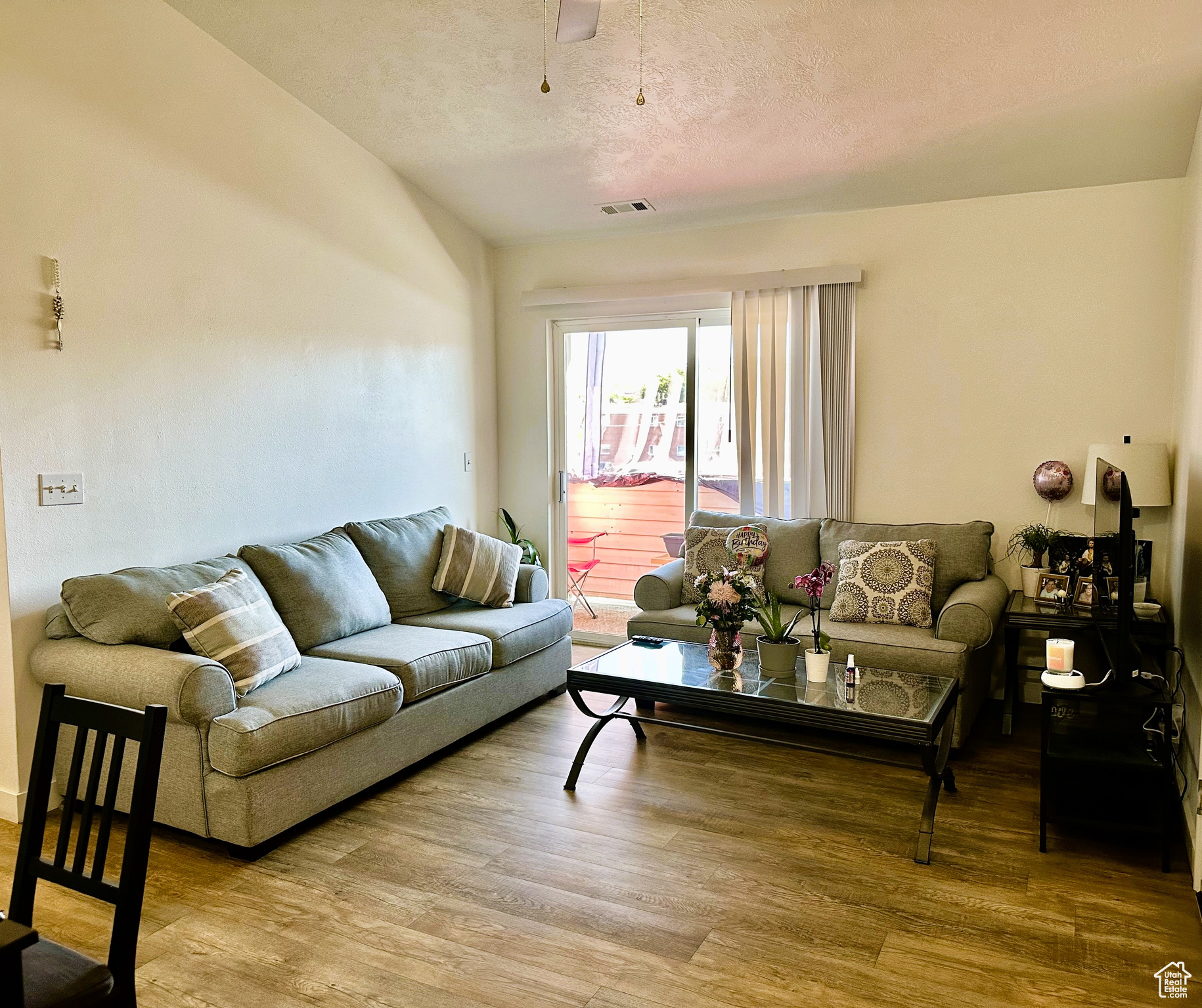 Living room featuring hardwood / wood-style flooring, ceiling fan, and a textured ceiling