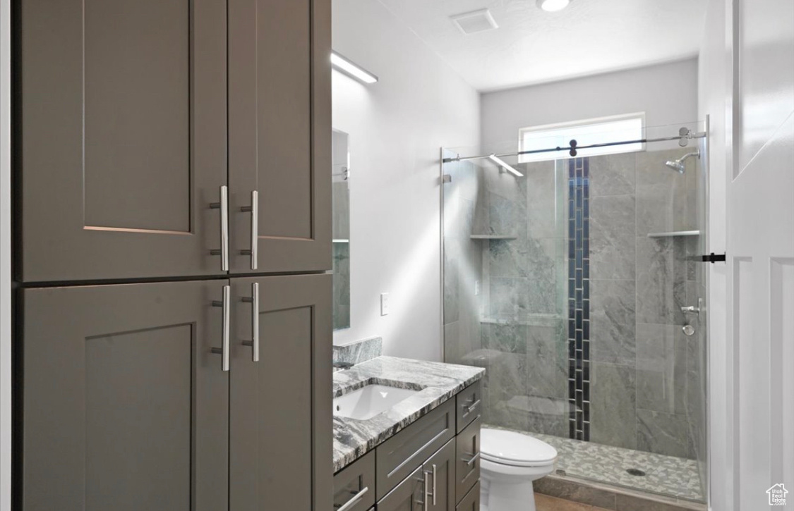 Bathroom featuring vanity, toilet, and an enclosed shower
