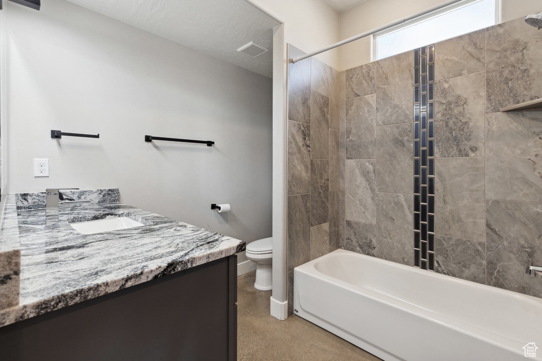 Full bathroom featuring tiled shower / bath, vanity, and toilet