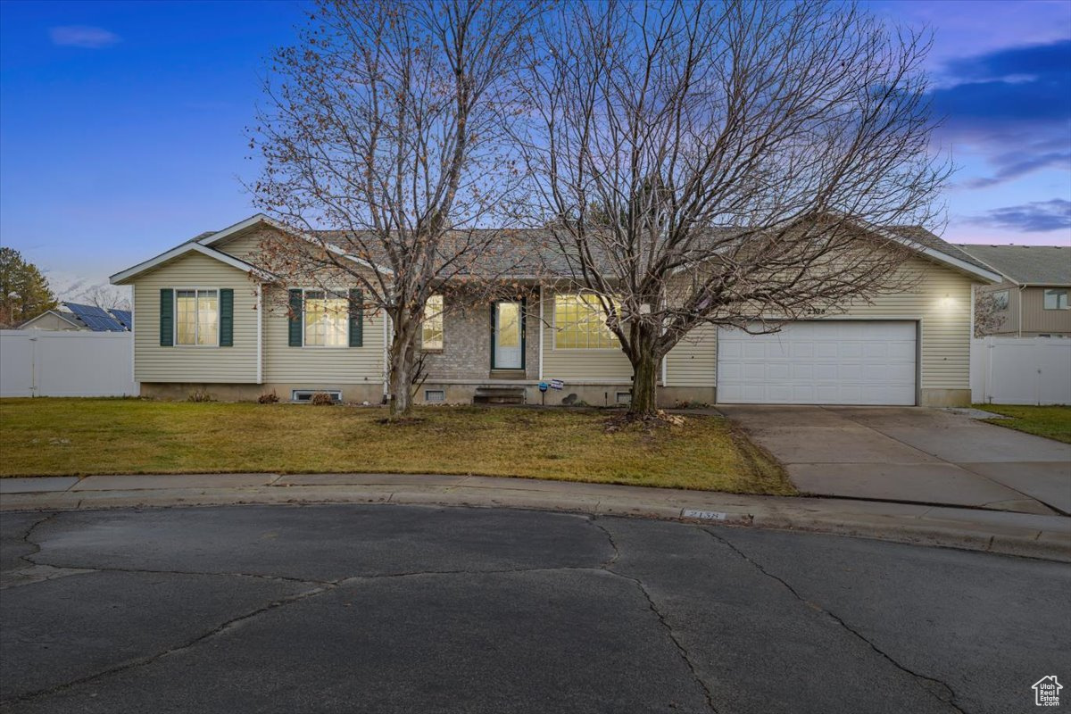 Ranch-style home featuring a garage and a lawn