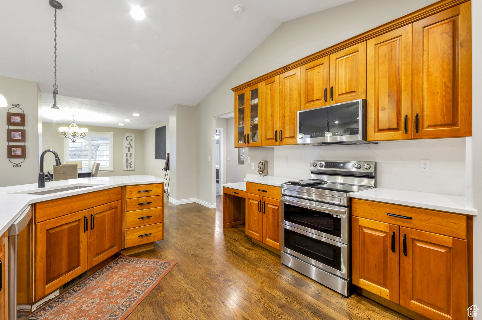 Kitchen with sink, an inviting chandelier, lofted ceiling, decorative light fixtures, and appliances with stainless steel finishes