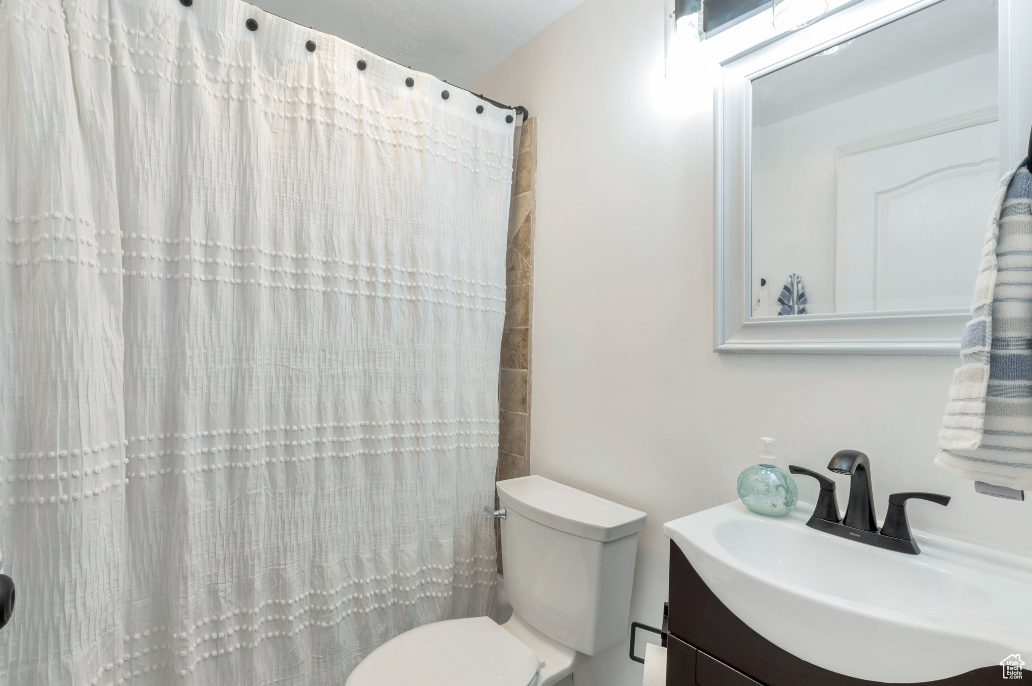 Bathroom with vanity, a shower with shower curtain, and toilet