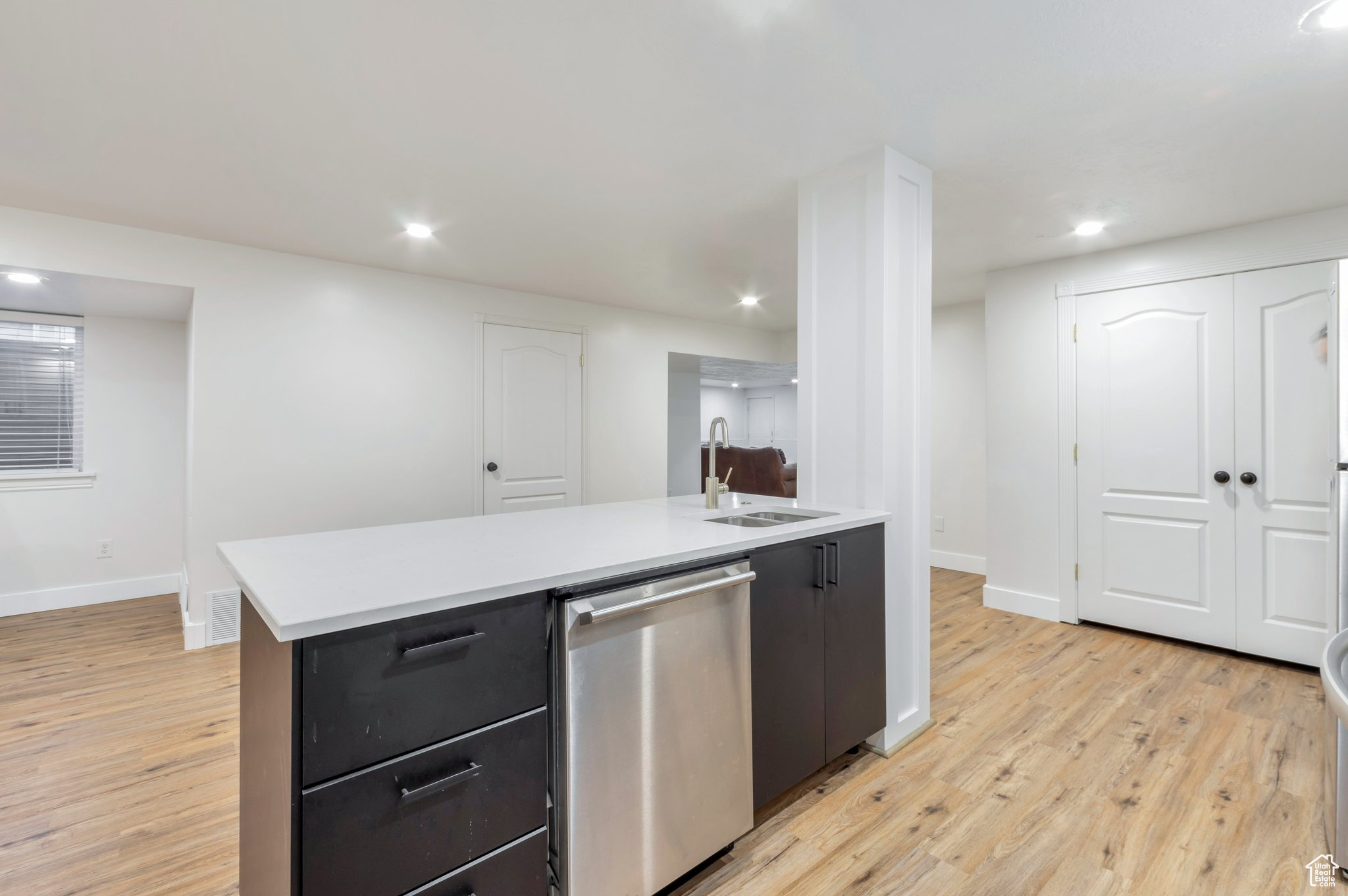 Kitchen with sink, dishwasher, a center island with sink, and light hardwood / wood-style flooring