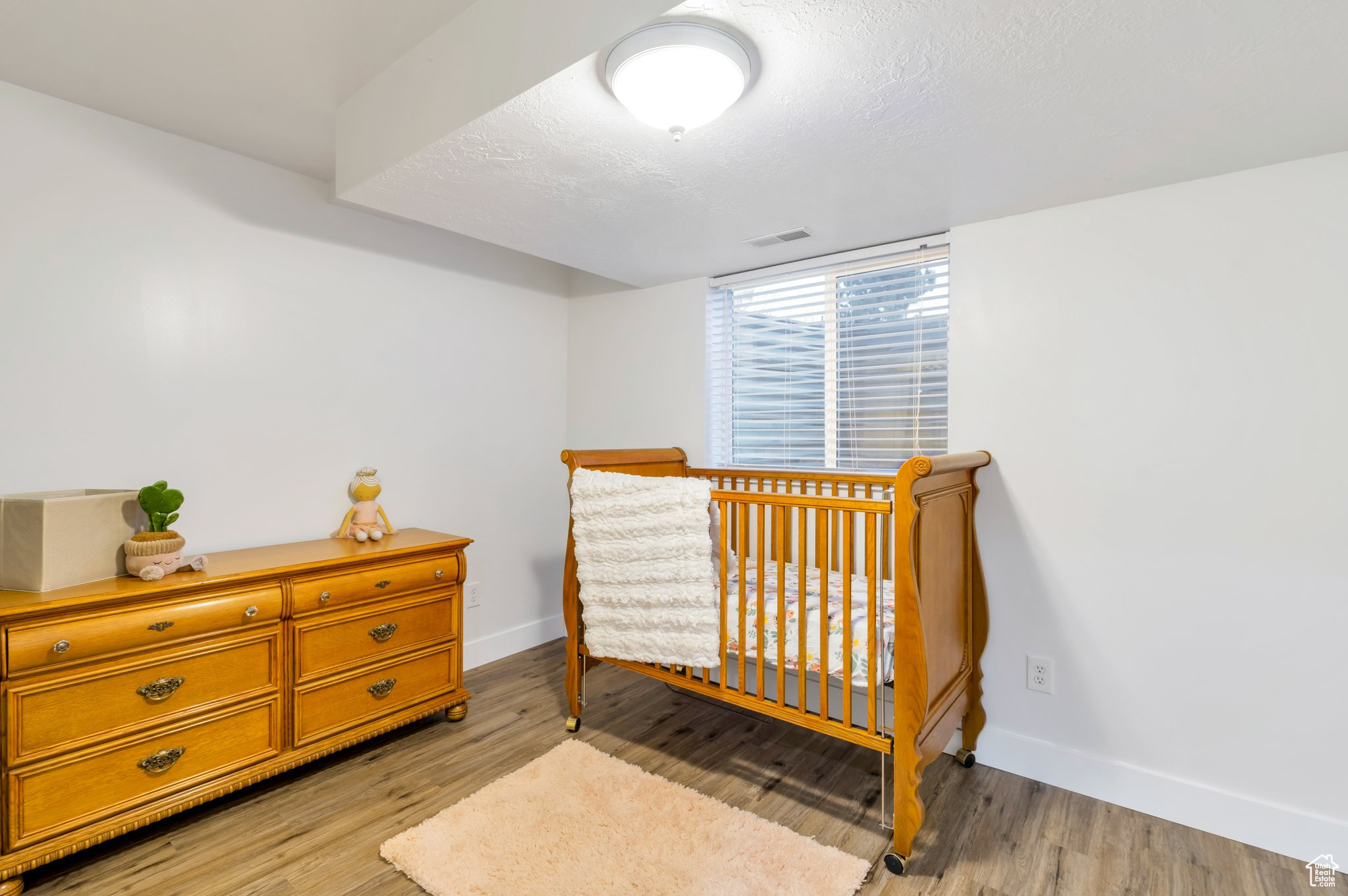 Bedroom with a nursery area and light hardwood / wood-style floors