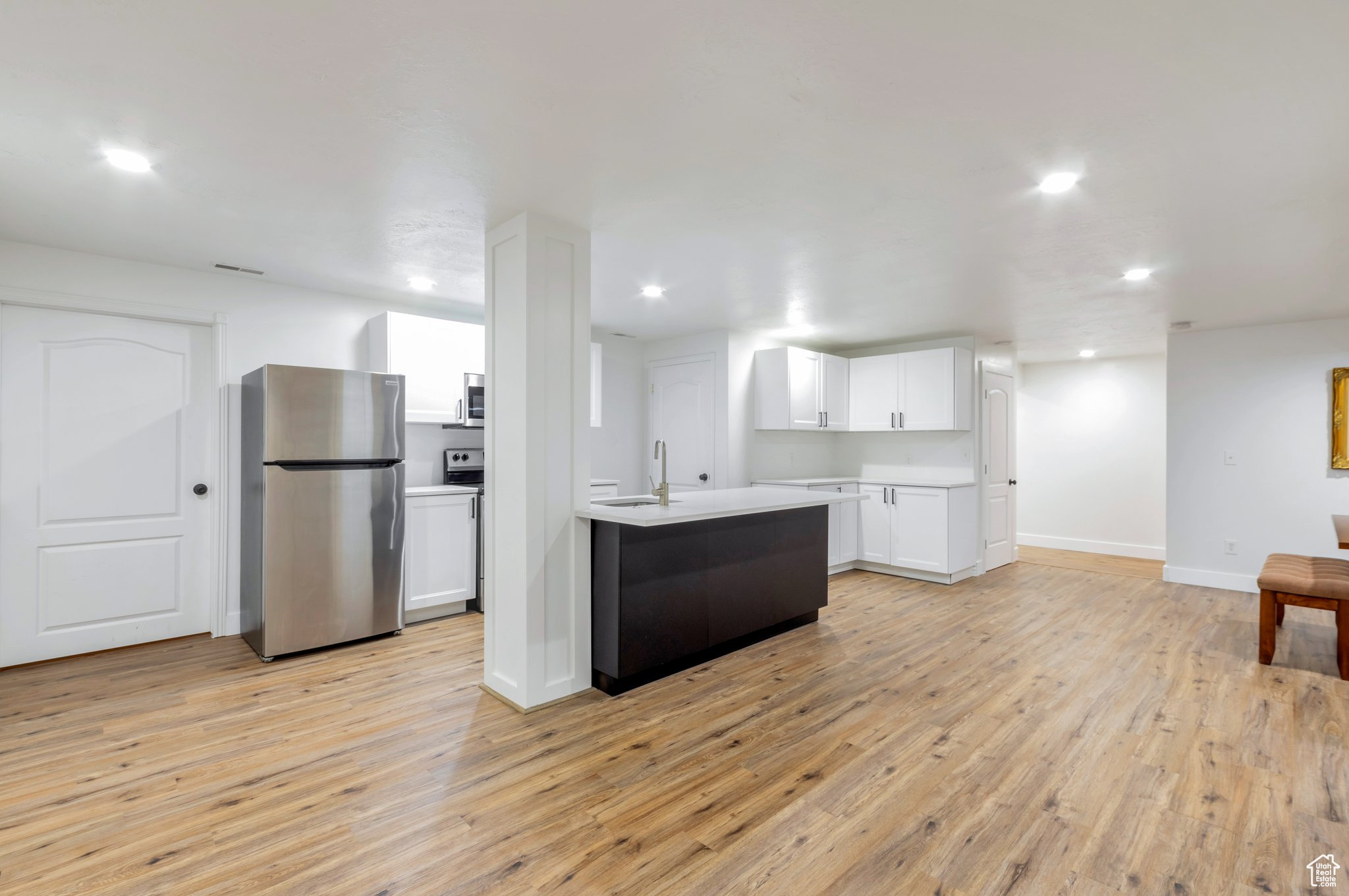 Kitchen with light hardwood / wood-style flooring, white cabinets, stainless steel appliances, and sink