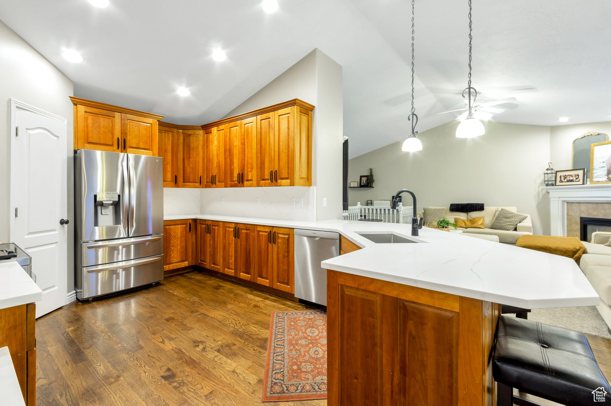 Kitchen with a tile fireplace, sink, stainless steel appliances, kitchen peninsula, and a breakfast bar