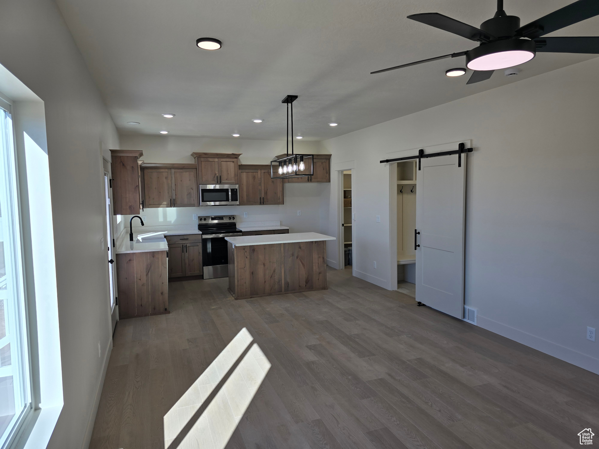 Kitchen featuring sink, hanging light fixtures, a barn door, a kitchen island, and appliances with stainless steel finishes