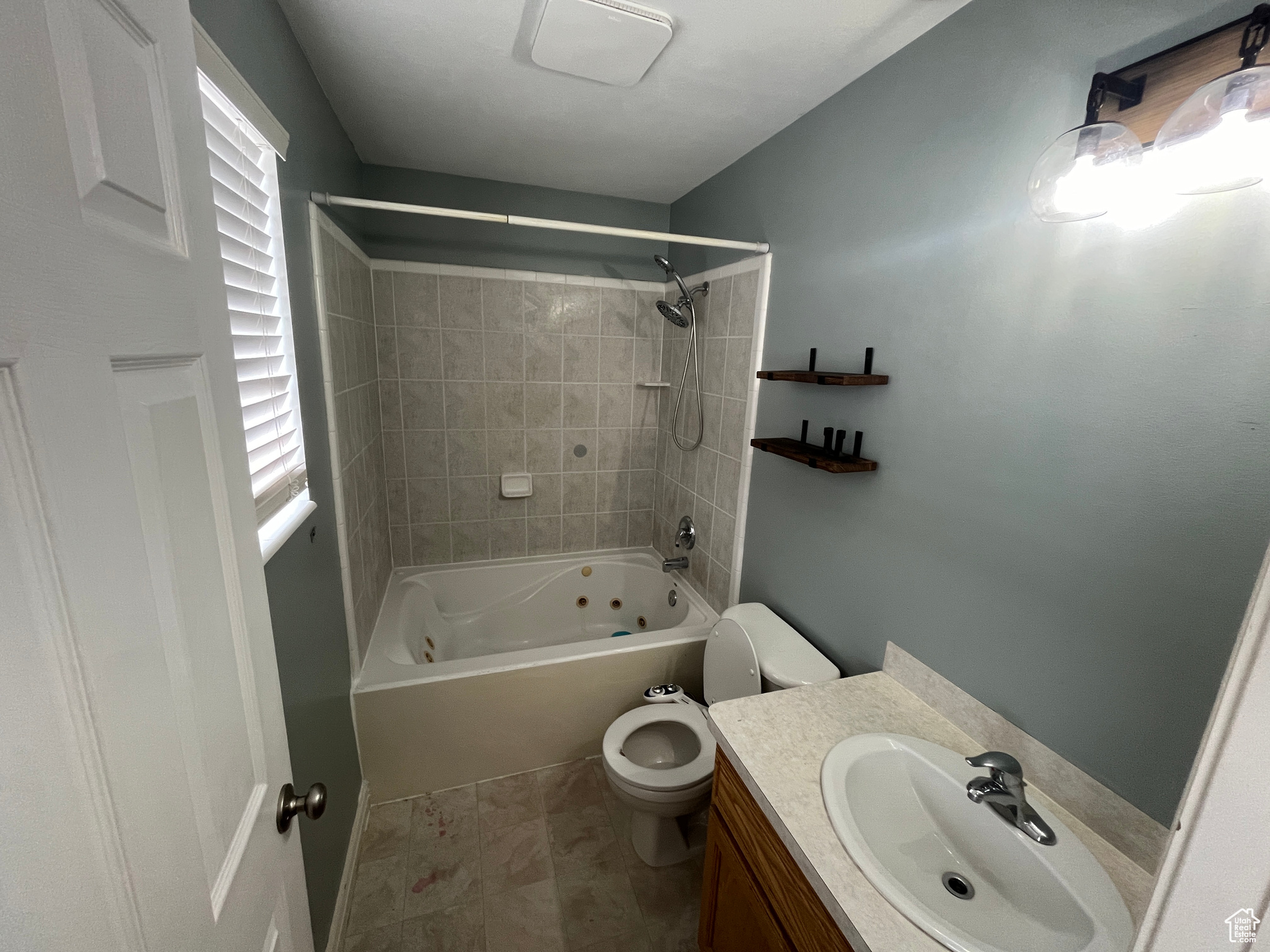 Full bathroom with tile patterned flooring, vanity, toilet, and tiled shower and jetted bath