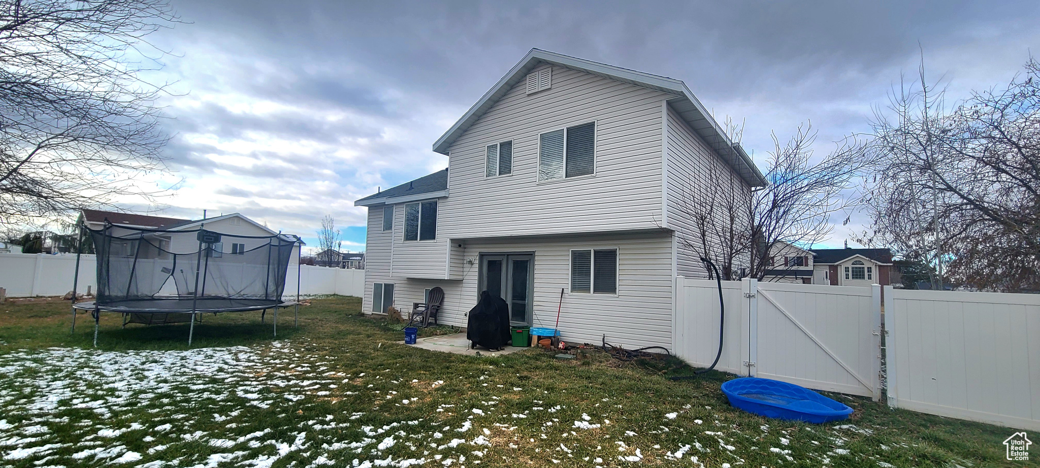 Rear view of property with a lawn and a trampoline