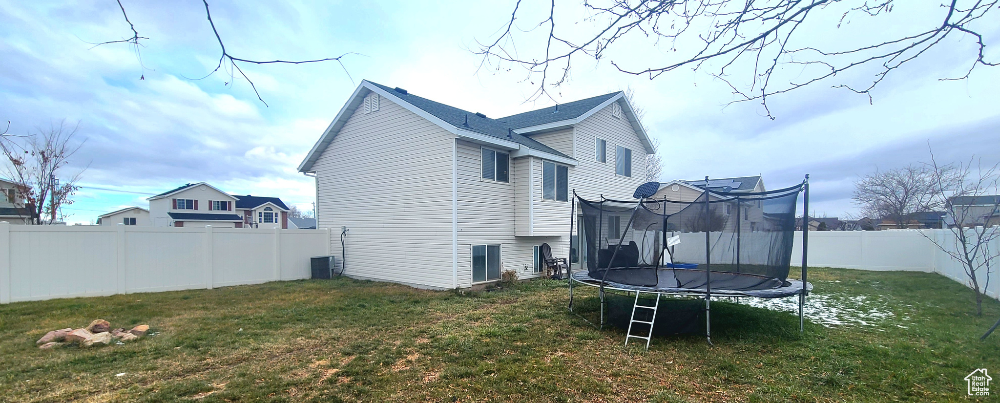 Back of property featuring a yard and a trampoline