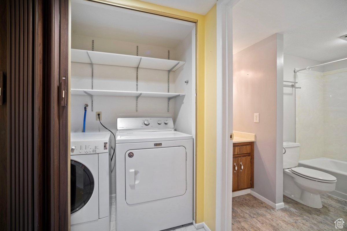 Washroom featuring washing machine and clothes dryer and light hardwood / wood-style flooring