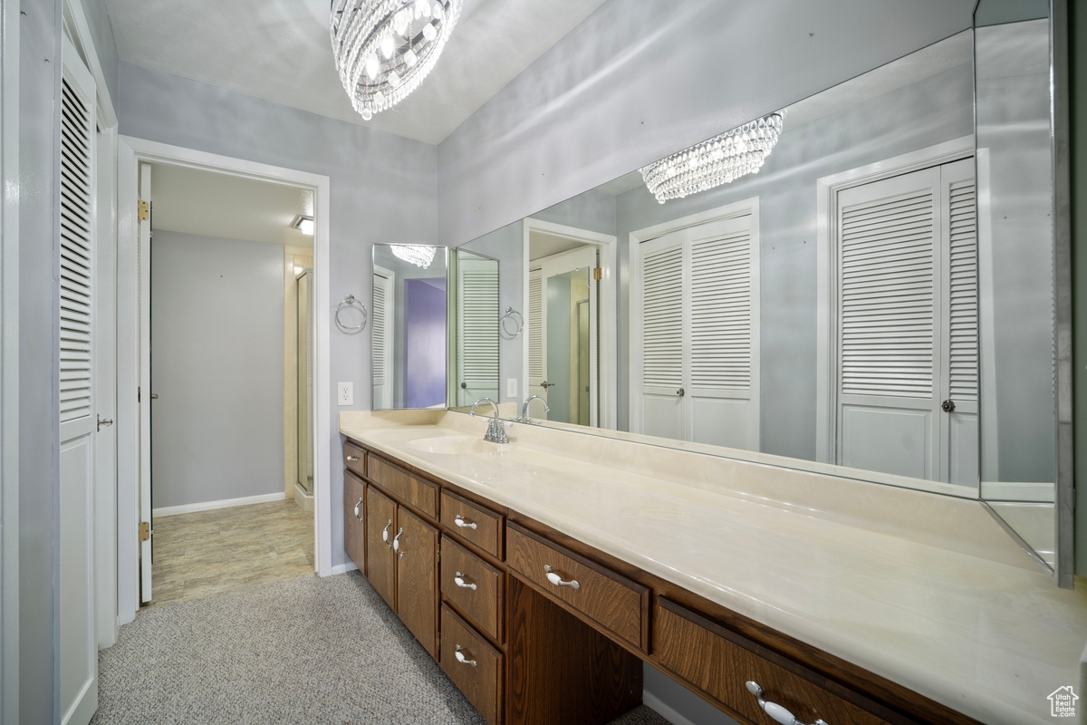 Bathroom with a shower with shower door, a chandelier, and vanity