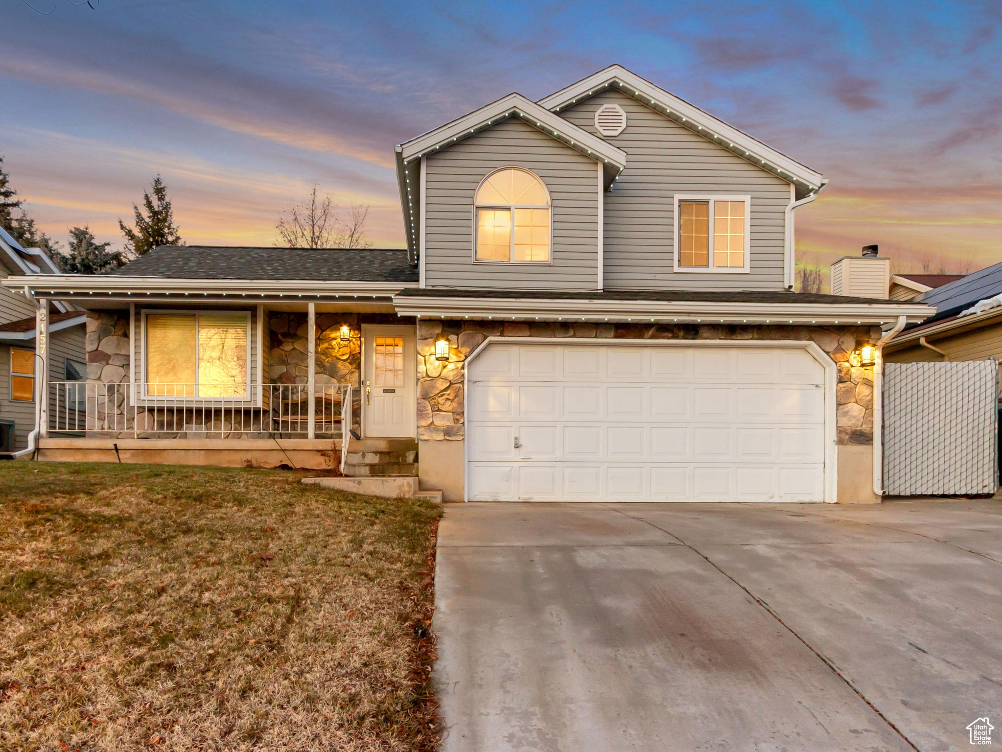 View of front property with a lawn, covered porch, central AC unit, and a garage