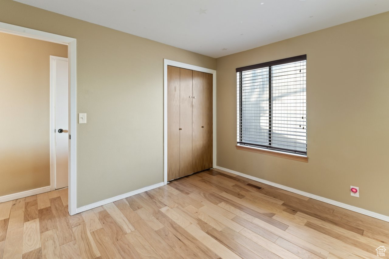 Unfurnished bedroom featuring light wood-type flooring and a closet