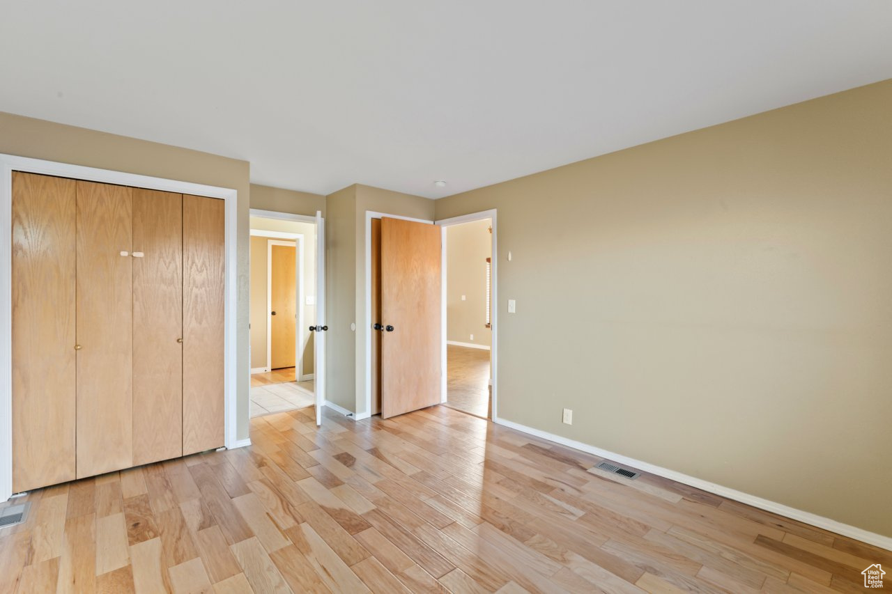 Unfurnished bedroom with a closet and light hardwood / wood-style floors