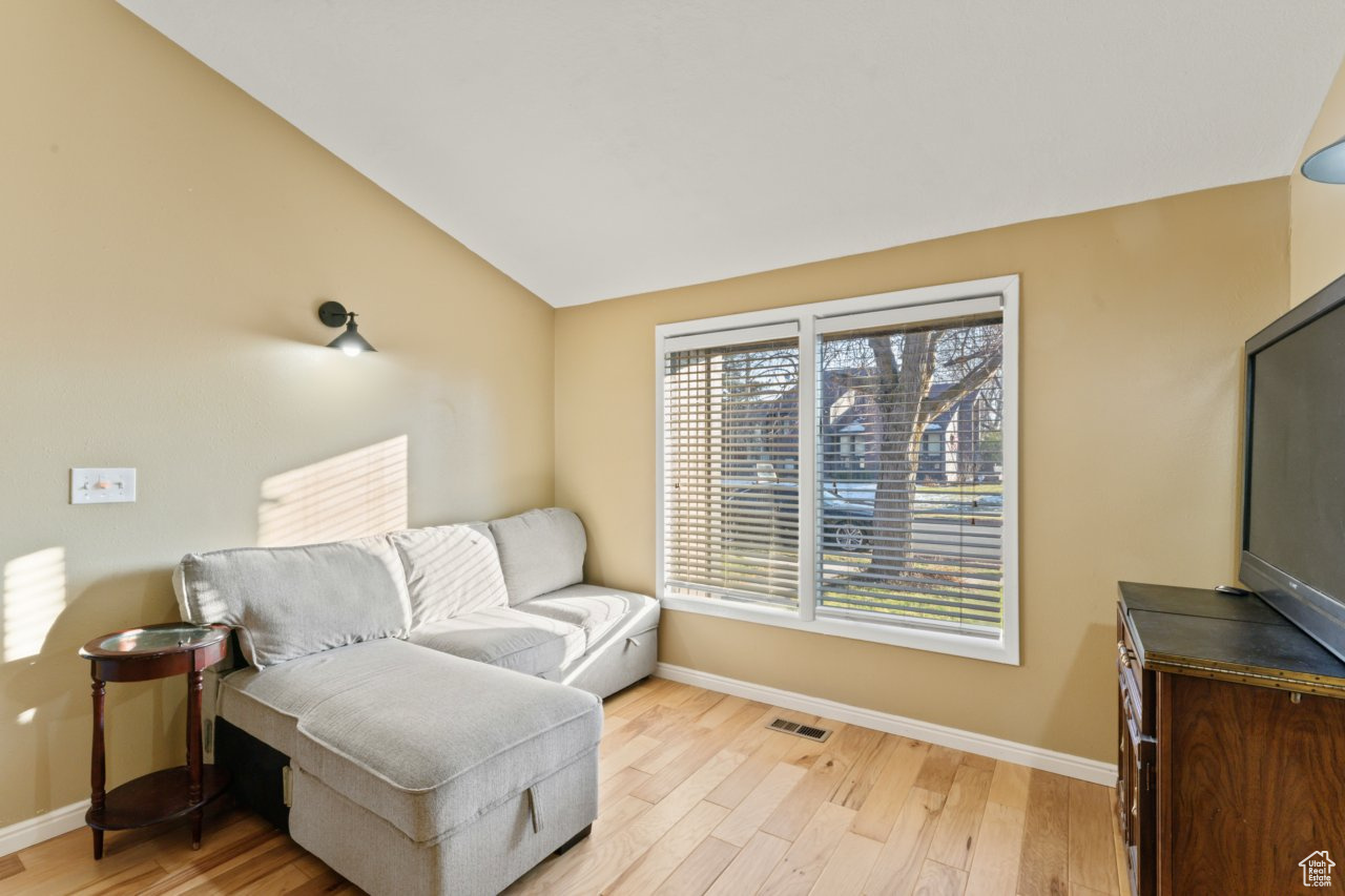 Living area with vaulted ceiling and light hardwood / wood-style floors