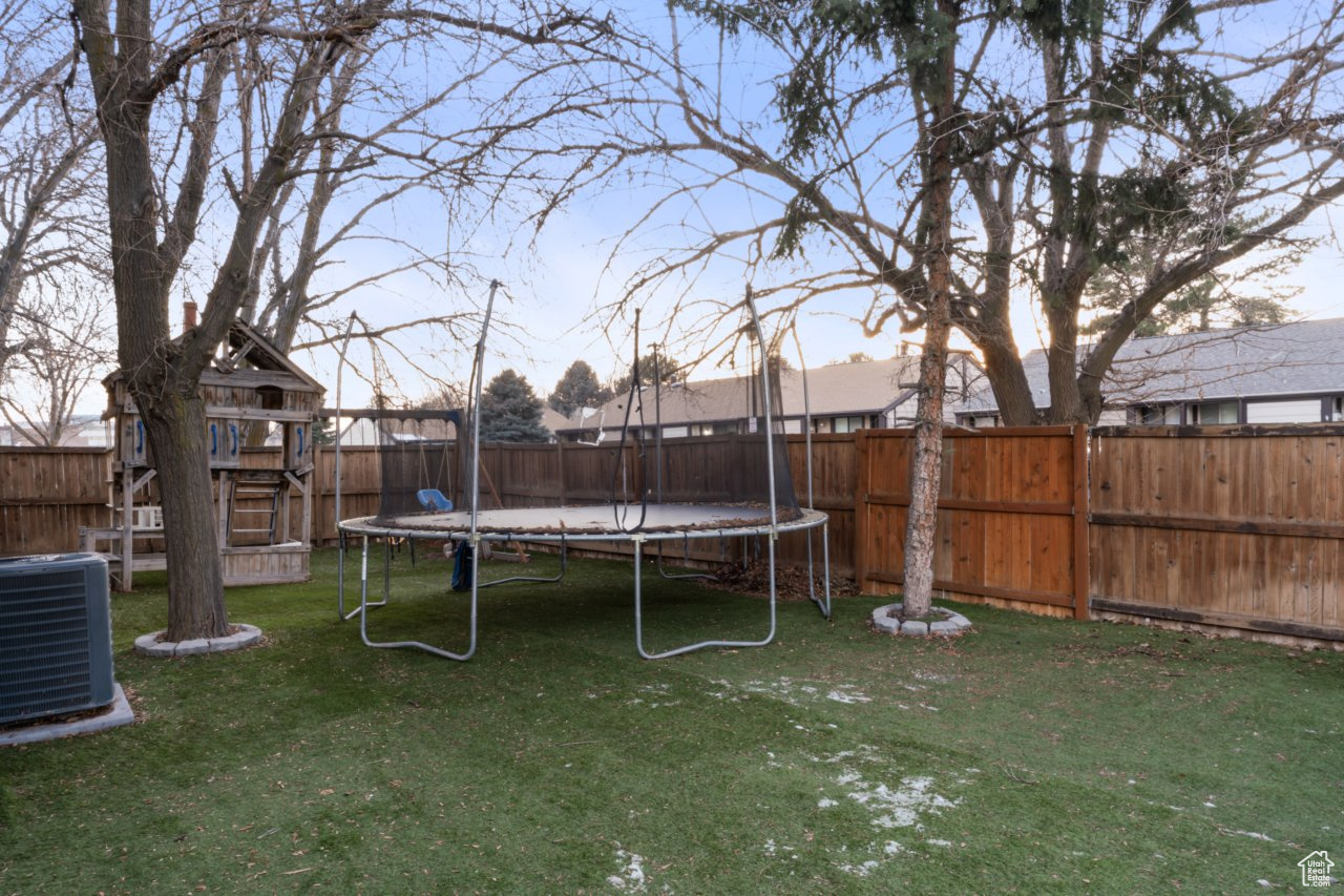 View of yard with cooling unit, a playground, and a trampoline