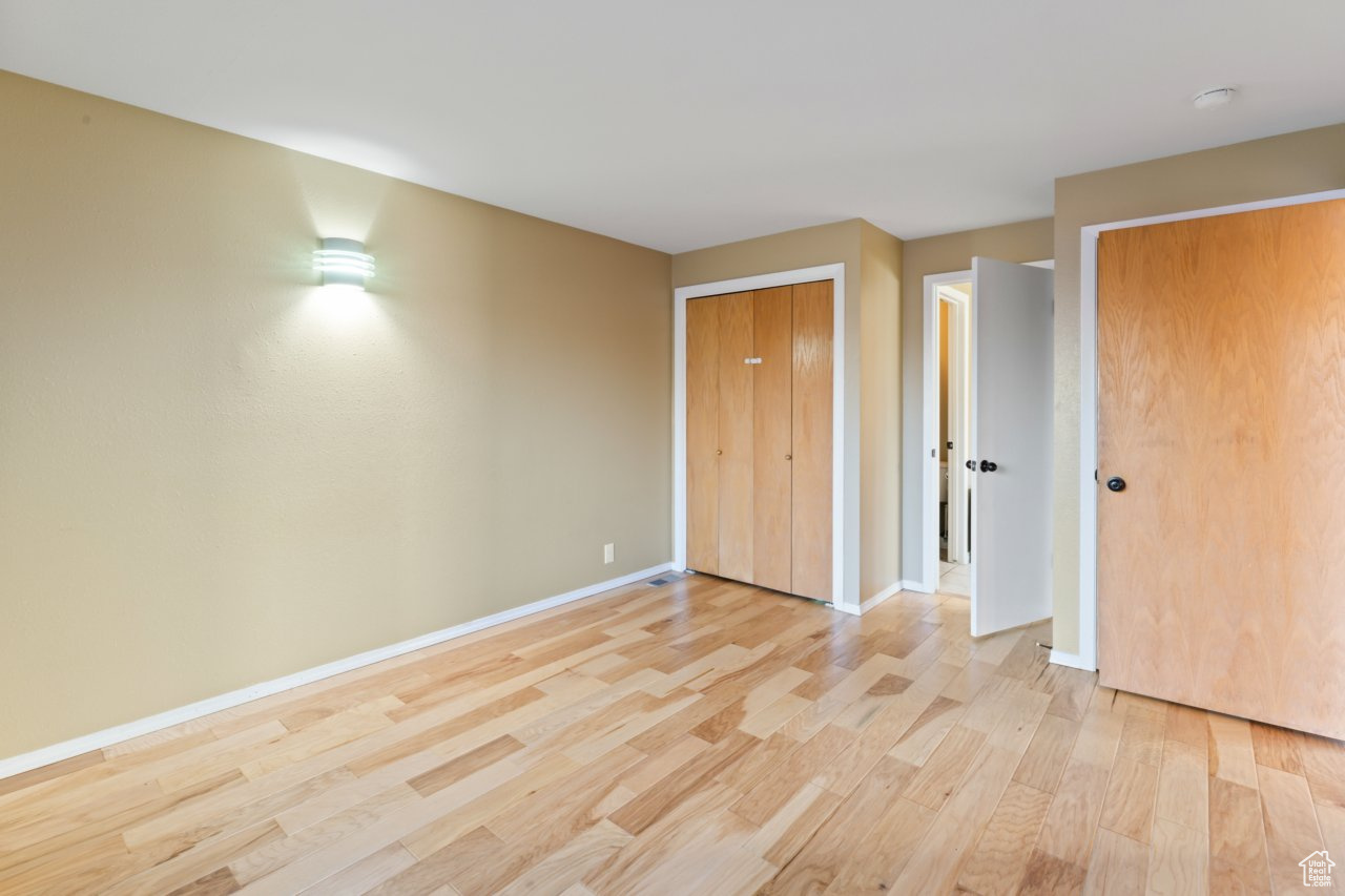 Unfurnished bedroom featuring multiple closets and light hardwood / wood-style floors