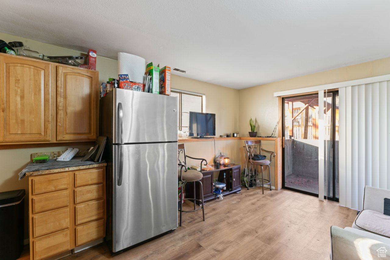 Kitchen with a healthy amount of sunlight, light hardwood / wood-style flooring, and stainless steel refrigerator