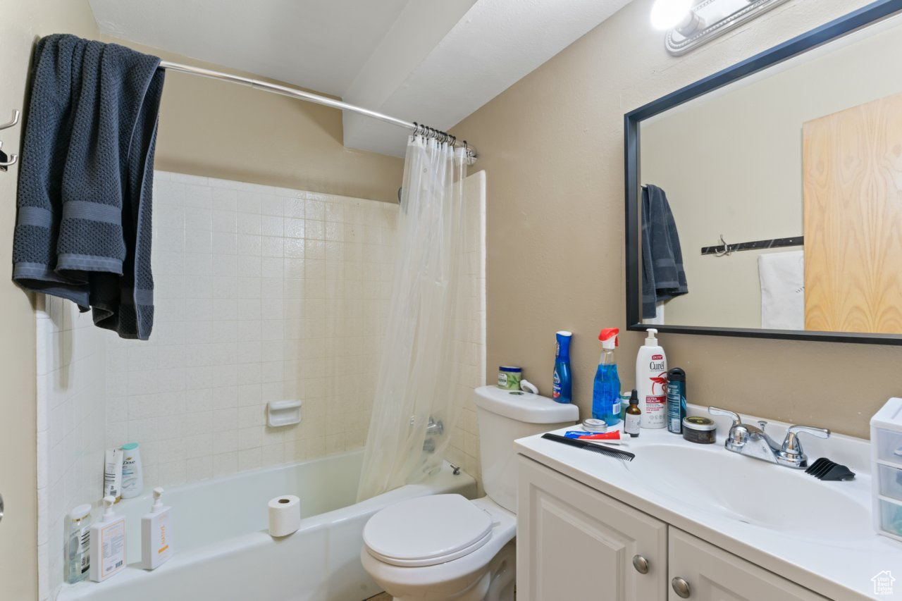 Full bathroom with toilet, vanity, and shower / bath combo