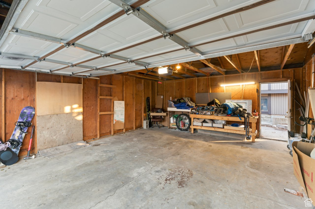 Garage featuring a workshop area, wood walls, and a garage door opener