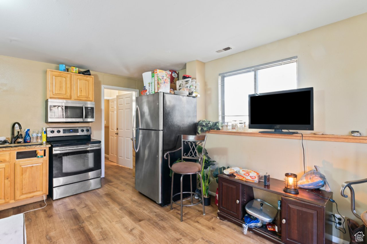 Kitchen featuring stainless steel appliances, light brown cabinetry, and wood-type flooring