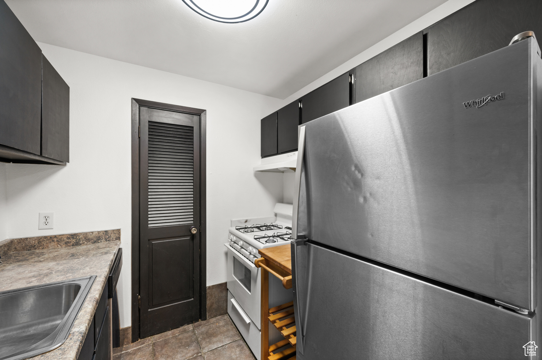 Kitchen featuring sink, range with gas cooktop, black dishwasher, and stainless steel fridge