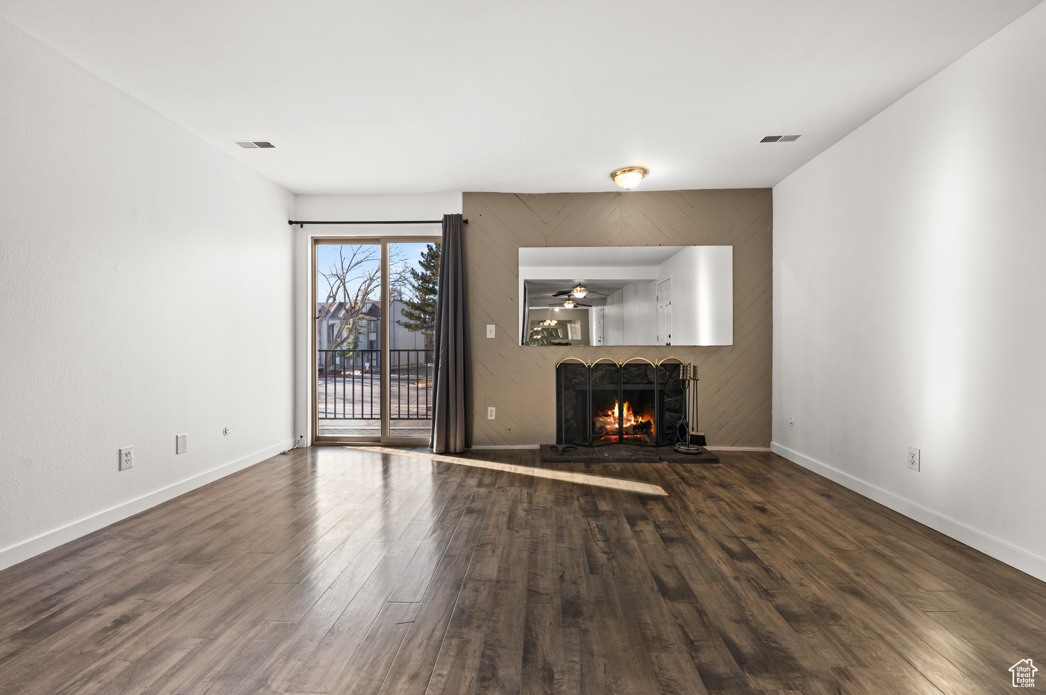 Unfurnished living room featuring ceiling fan and dark hardwood / wood-style floors