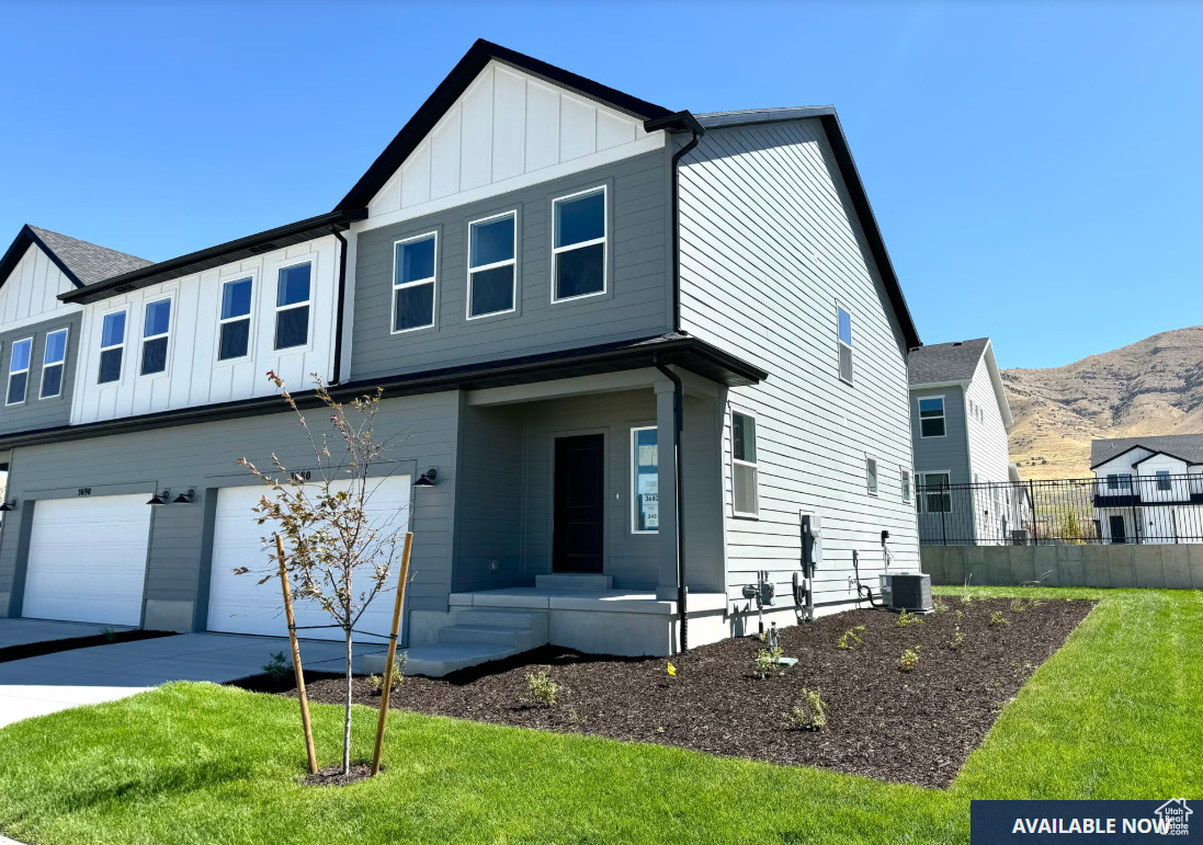 View of front of property with a mountain view, central AC, a garage, and a front yard