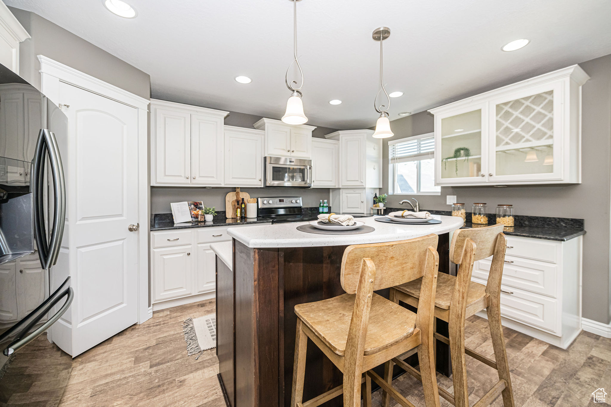 Kitchen with stainless steel appliances, a kitchen island, pendant lighting, and light hardwood / wood-style floors