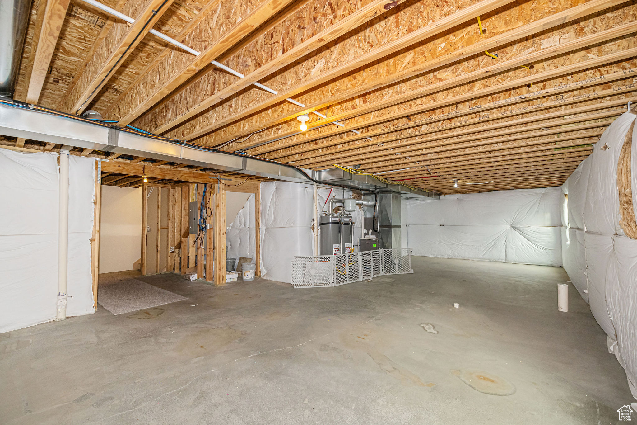 Basement featuring electric panel, heating unit, and water heater