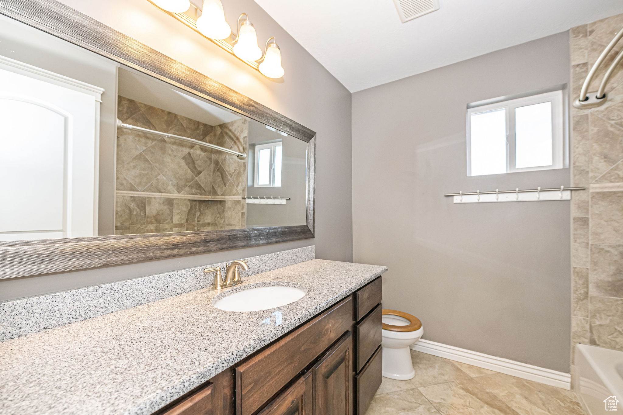 Full bathroom featuring toilet, vanity, tile patterned flooring, and tiled shower / bath