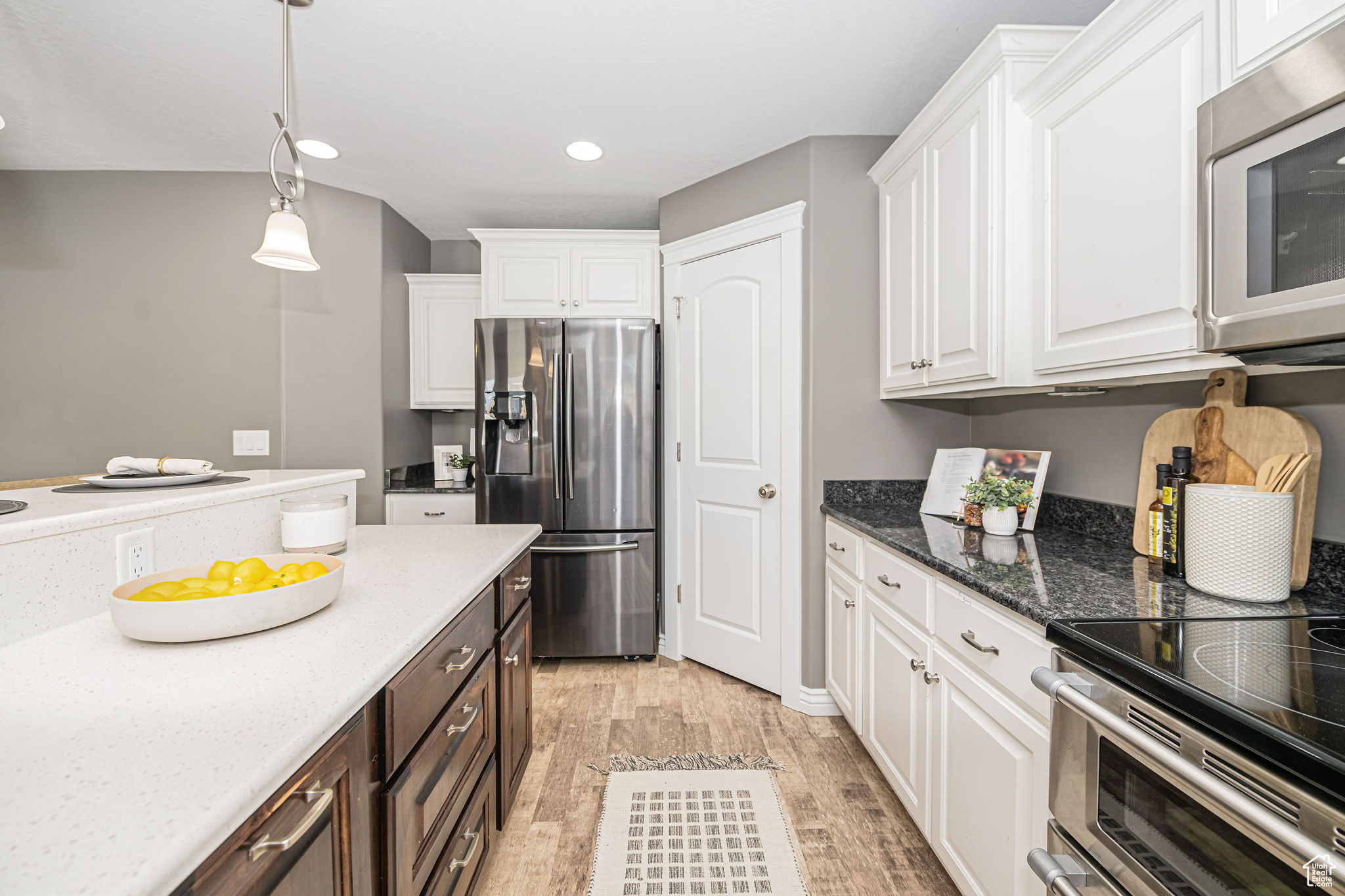 Kitchen with appliances with stainless steel finishes, white cabinetry, and light hardwood / wood-style floors