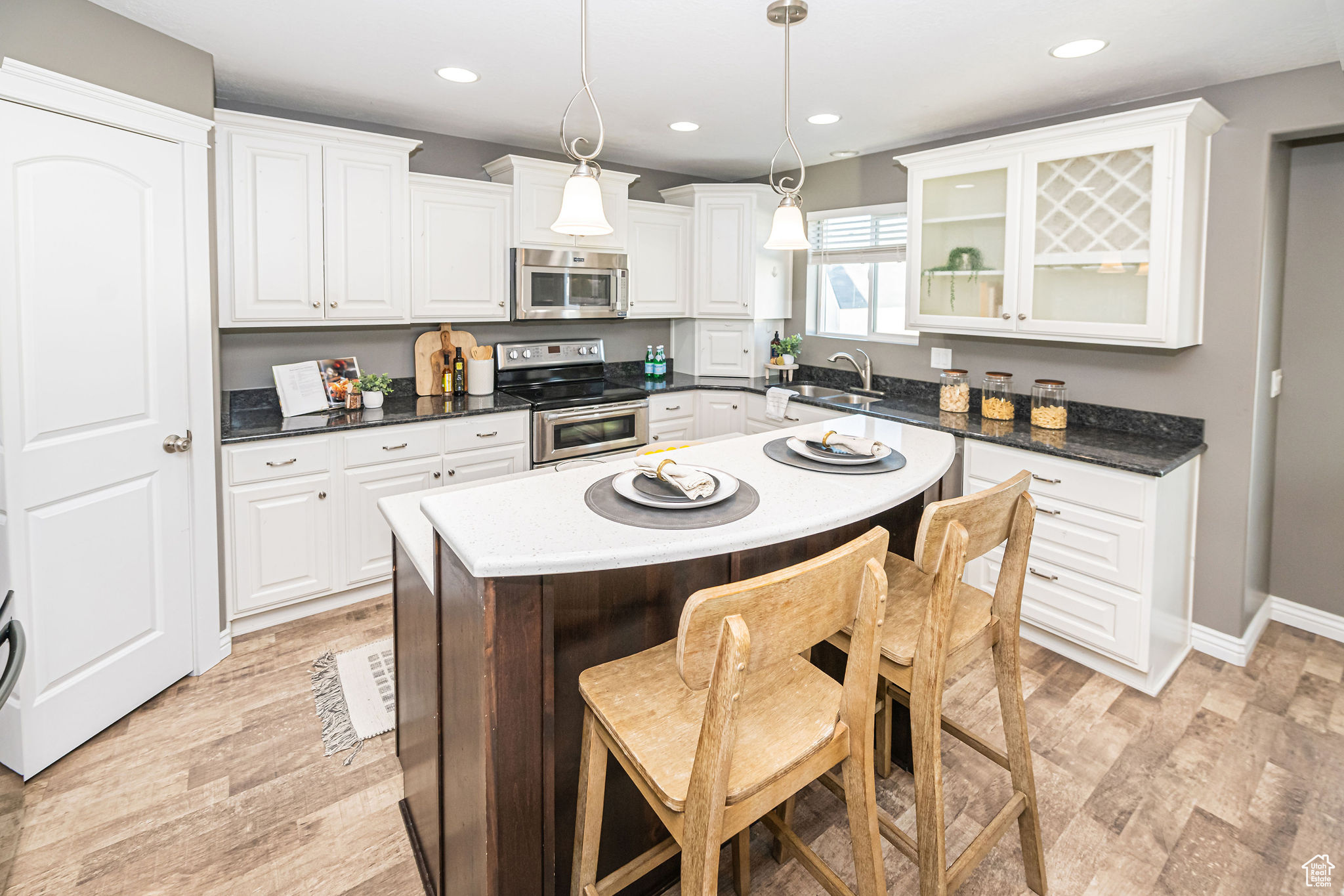 Kitchen featuring stainless steel appliances, white cabinetry, a center island, and hanging light fixtures