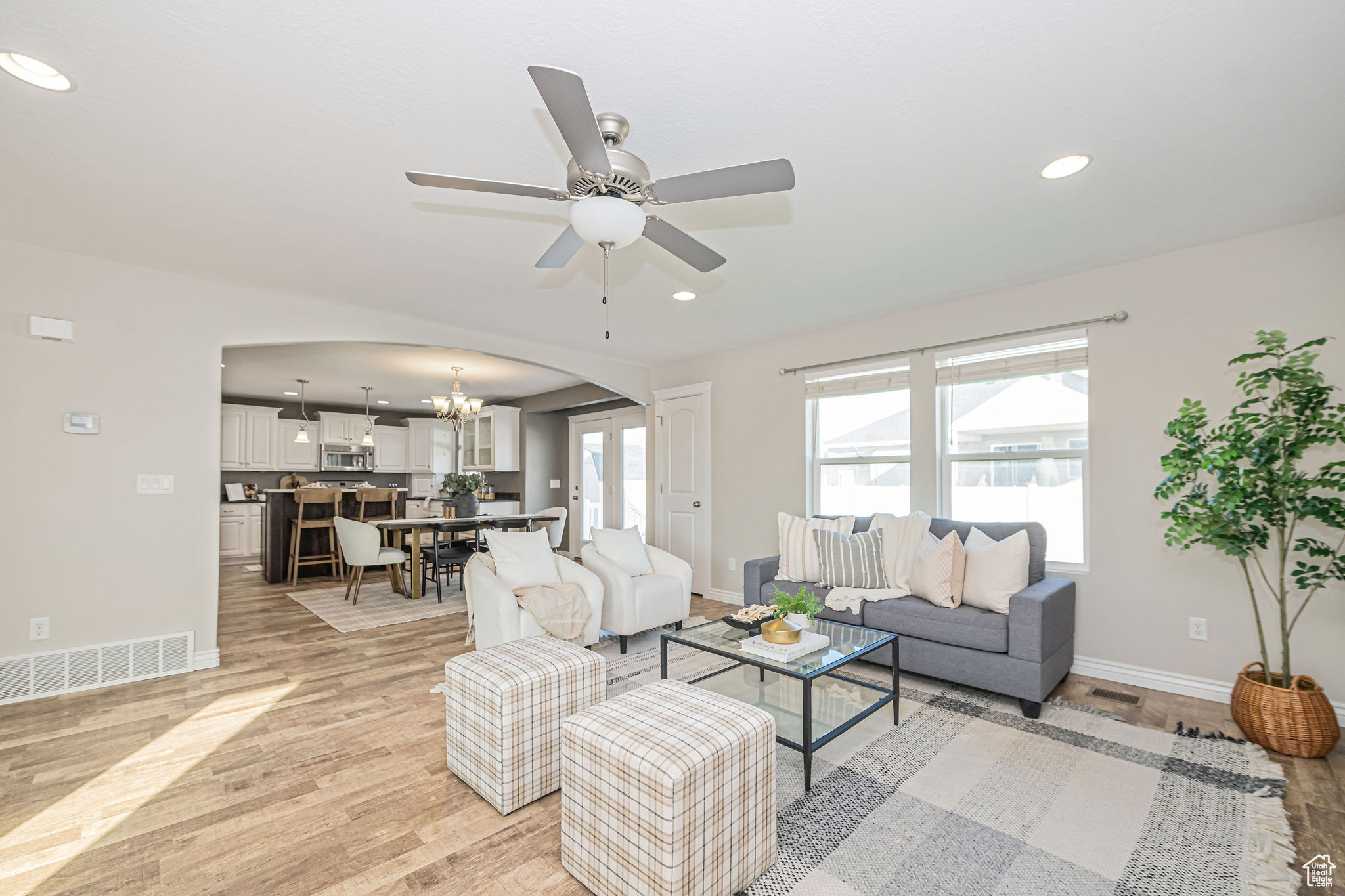 Living room with ceiling fan with notable chandelier and light hardwood / wood-style flooring